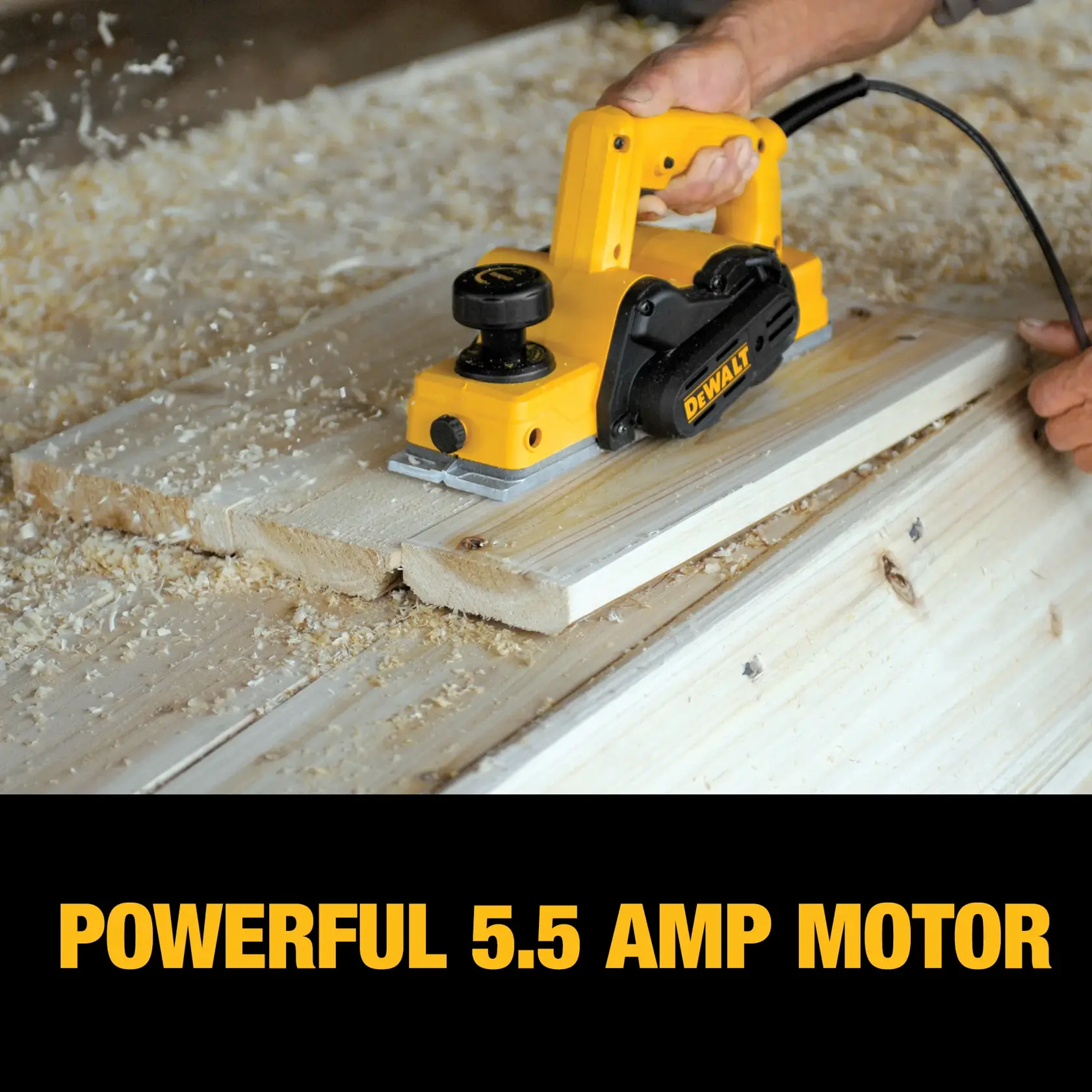 A DEWALT electric hand planer with a powerful 5.5 amp motor is being used to smooth the surface of wooden boards, with wood shavings scattered around.