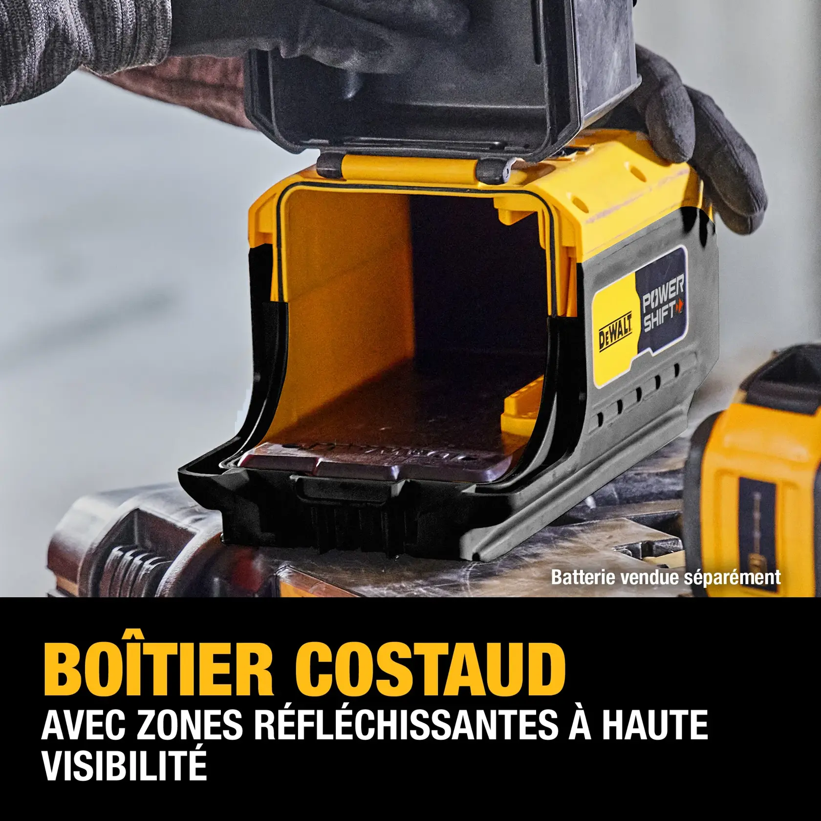 A close-up of a DEWALT Power Shift device with an open, durable yellow and black housing. The device features high-visibility reflective zones. A gloved hand is opening the compartment, and the text on the image highlights the durable housing and high-visibility reflective zones. Battery is sold separately.