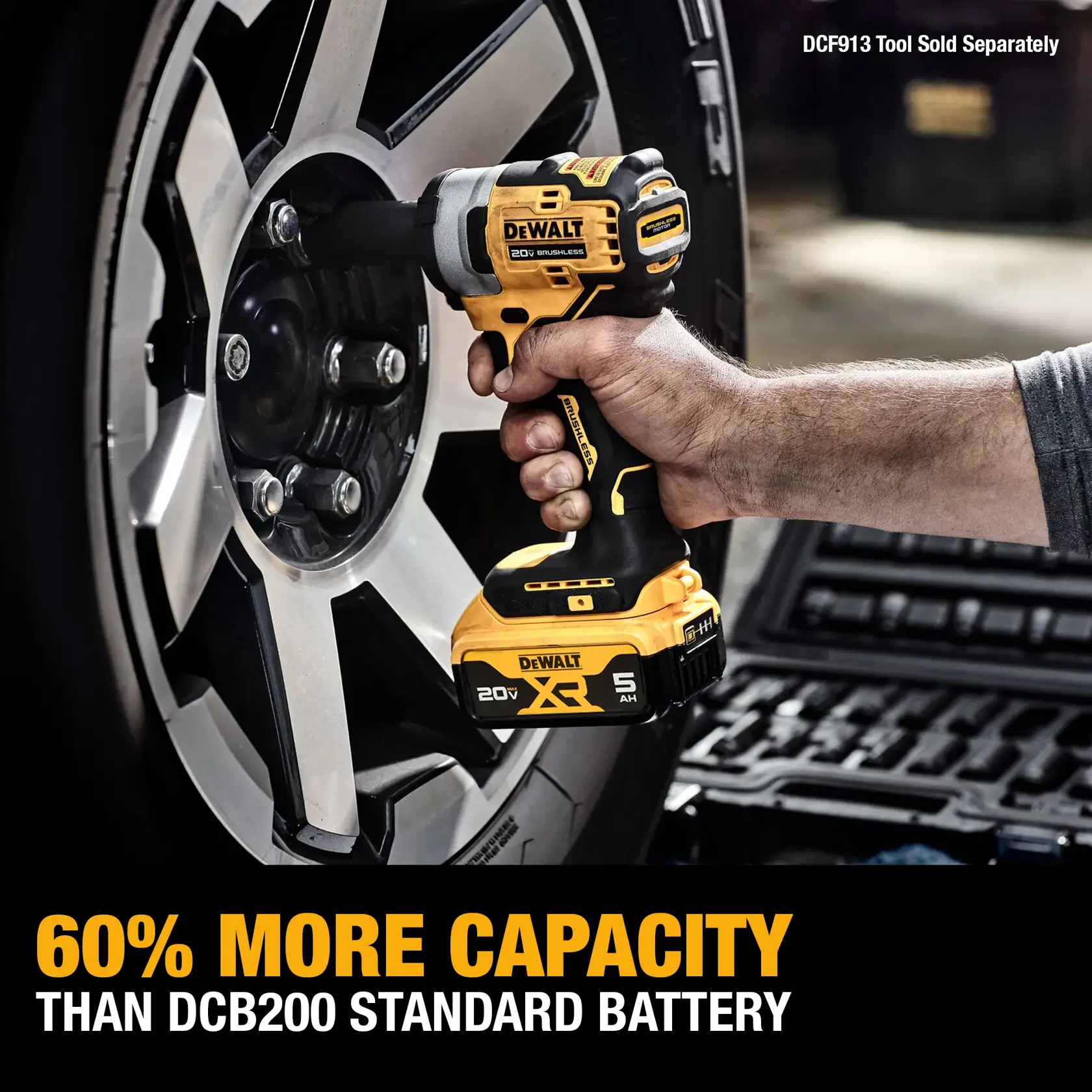 A person is using a DEWALT cordless power tool with a DCB205-2 20V XR 5Ah battery to work on a car tire. The image highlights that this battery has 60% more capacity than the DCB200 standard battery.