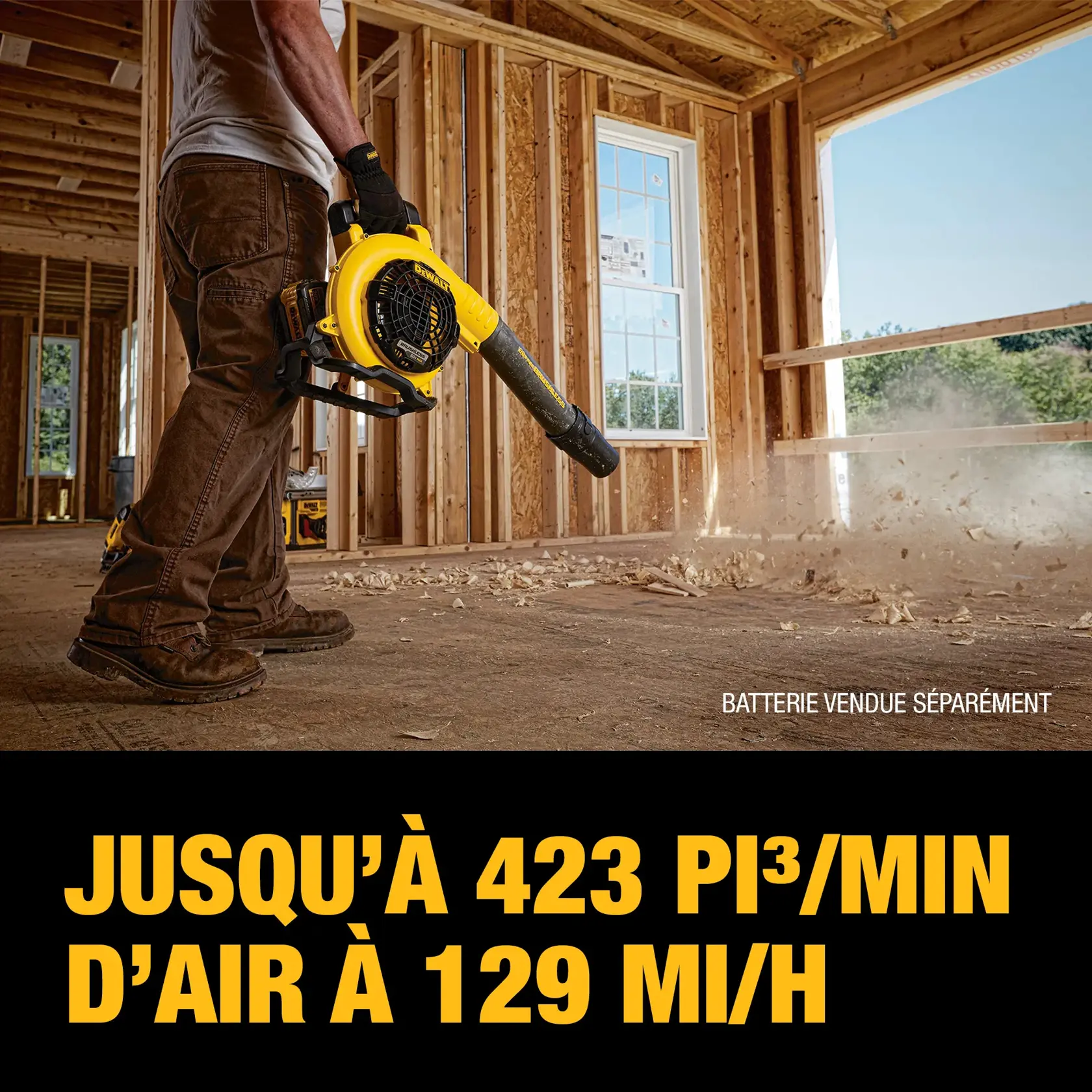 A person using a DEWALT handheld blower inside a wooden construction site. The blower is scattering debris on the floor. Text reads: 'Up to 423 CFM air volume at 129 MPH.' A note on the image indicates 'Battery sold separately.'