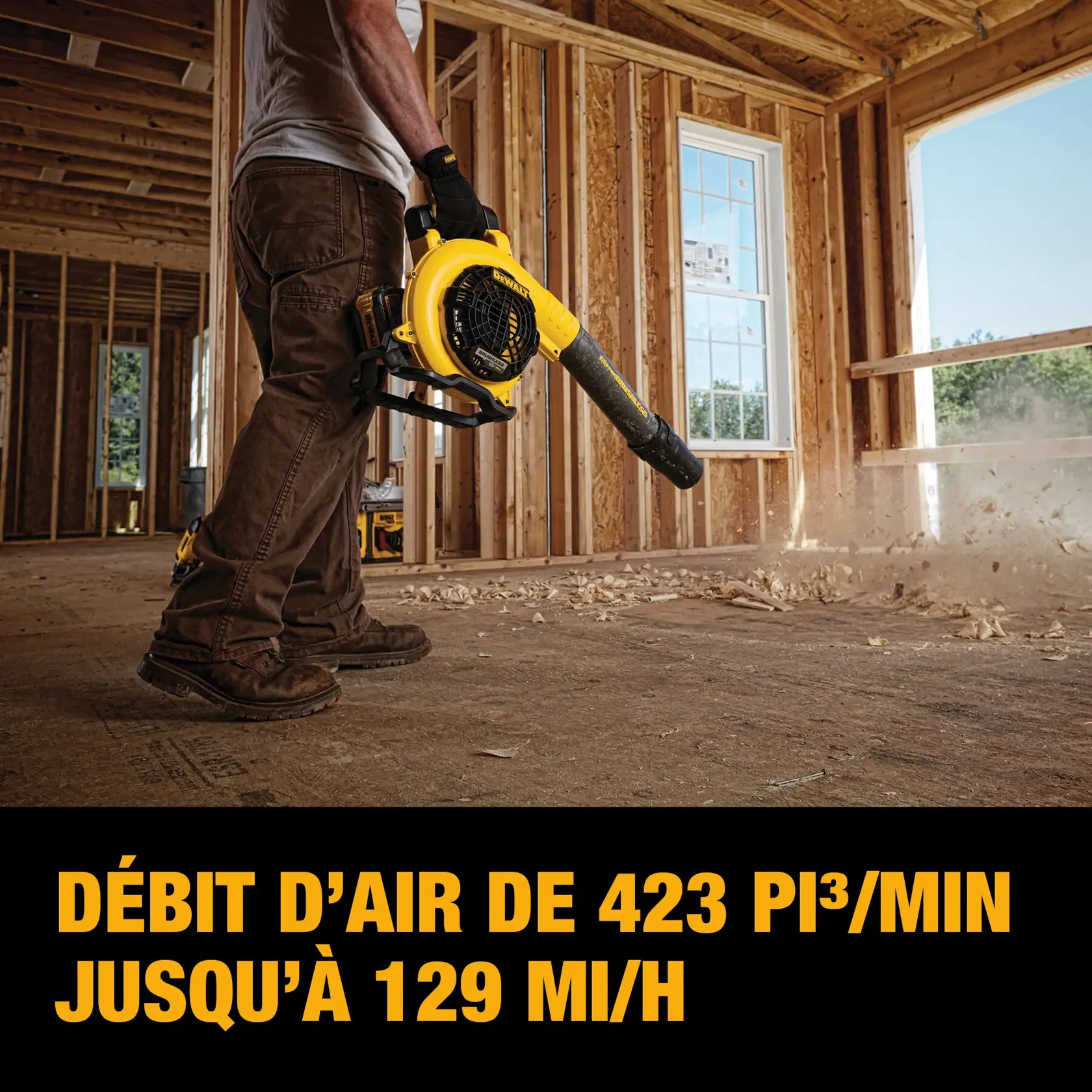 A person in workwear using a DEWALT cordless blower to clear debris on the floor of a wooden-framed house under construction. The text highlights airflow of 423 cubic feet per minute and speeds up to 129 miles per hour.