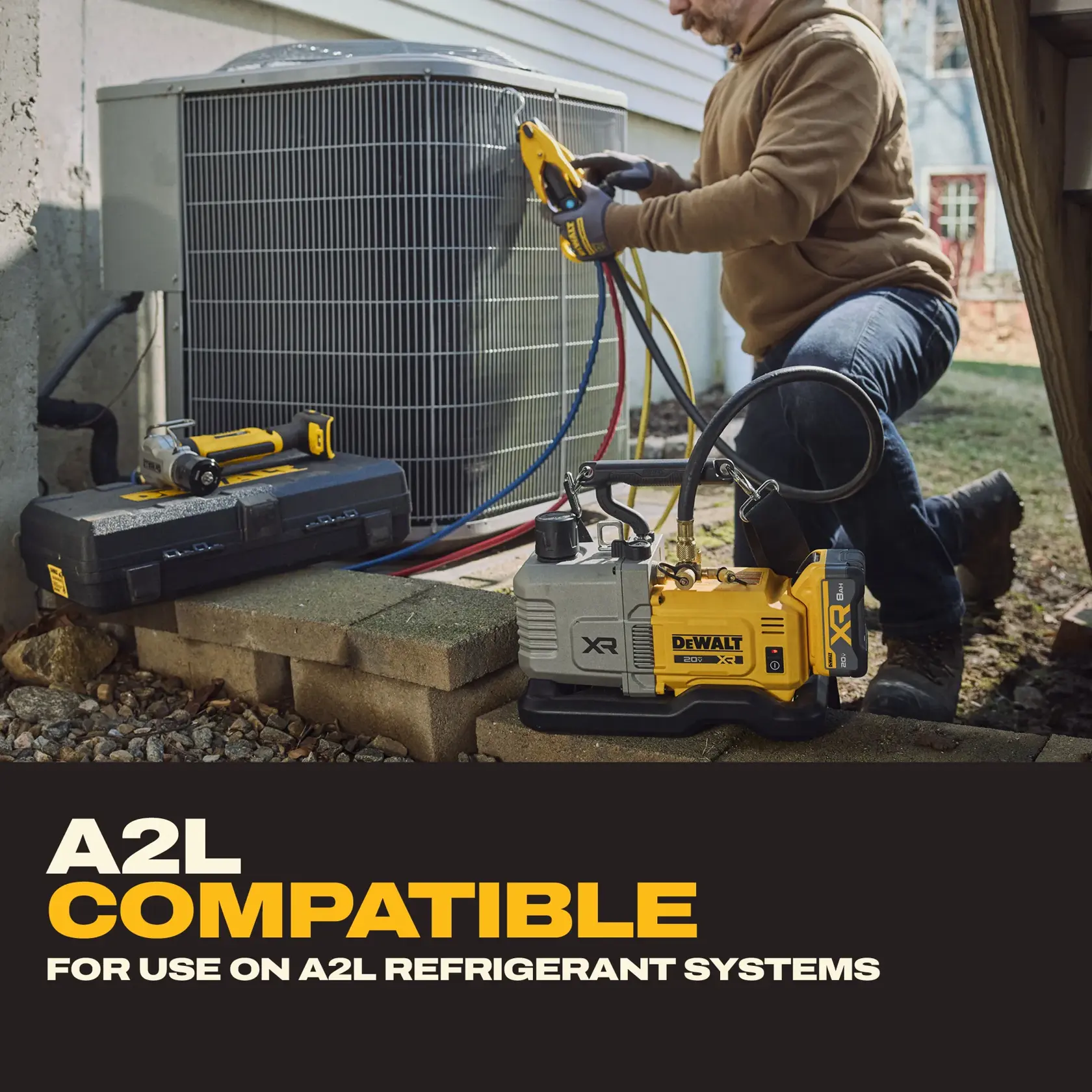 A person is servicing an outdoor HVAC unit using DEWALT tools. The image shows a DEWALT vacuum pump labeled XR placed nearby, with hoses connected to the HVAC system. A DEWALT tool case and another tool are also visible. Text on the image highlights that the product is A2L compatible and intended for use on A2L refrigerant systems.
