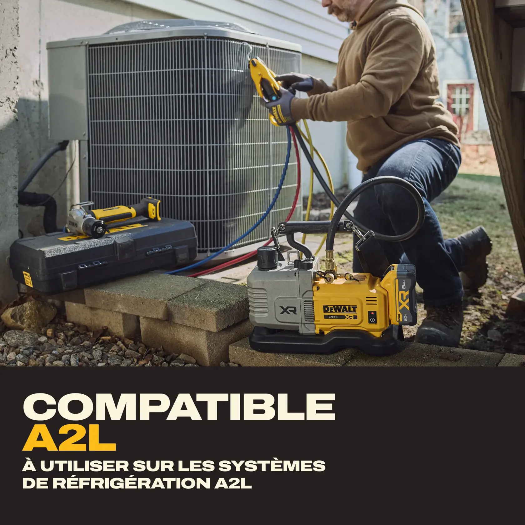 A person is servicing an outdoor HVAC unit using DEWALT tools. The image shows a DEWALT vacuum pump labeled XR placed nearby, with hoses connected to the HVAC system. A DEWALT tool case and another tool are also visible. Text on the image highlights that the product is A2L compatible and intended for use on A2L refrigerant systems.