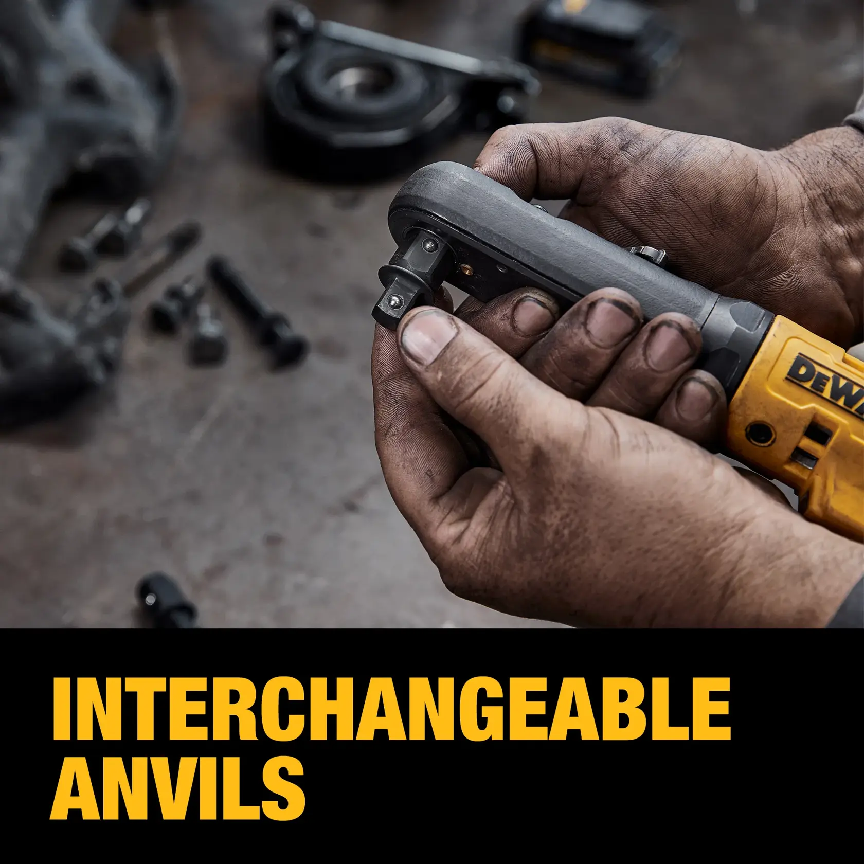 A close-up of dirty hands holding a DEWALT power tool with an interchangeable anvil, on a workshop table with scattered bolts and mechanical parts. The text 'INTERCHANGEABLE ANVILS' is displayed in bold yellow letters at the bottom.