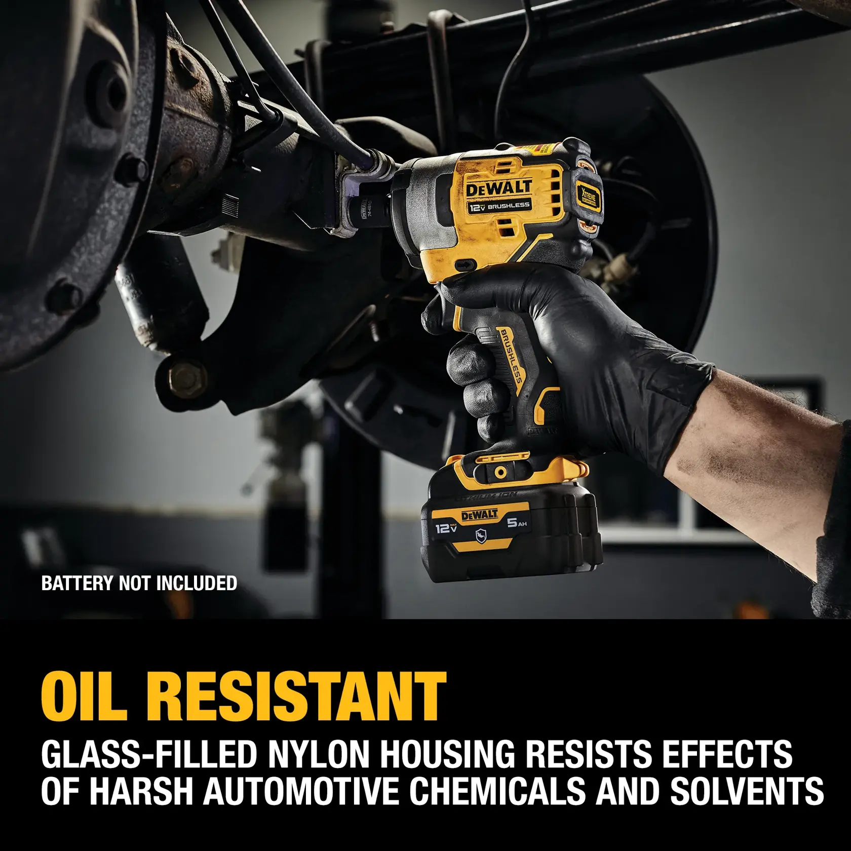A person wearing a black glove uses a DEWALT 12V brushless cordless impact wrench under a vehicle. The image highlights the tool's oil-resistant, glass-filled nylon housing, which helps resist harsh automotive chemicals and solvents. Text on the image notes that the battery is not included.