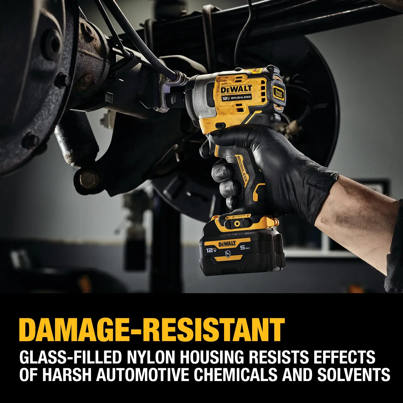 A person wearing a black glove uses a DEWALT 12V brushless cordless impact wrench on an automotive part. Text on the image highlights the tool's damage-resistant glass-filled nylon housing, which resists effects of harsh automotive chemicals and solvents.
