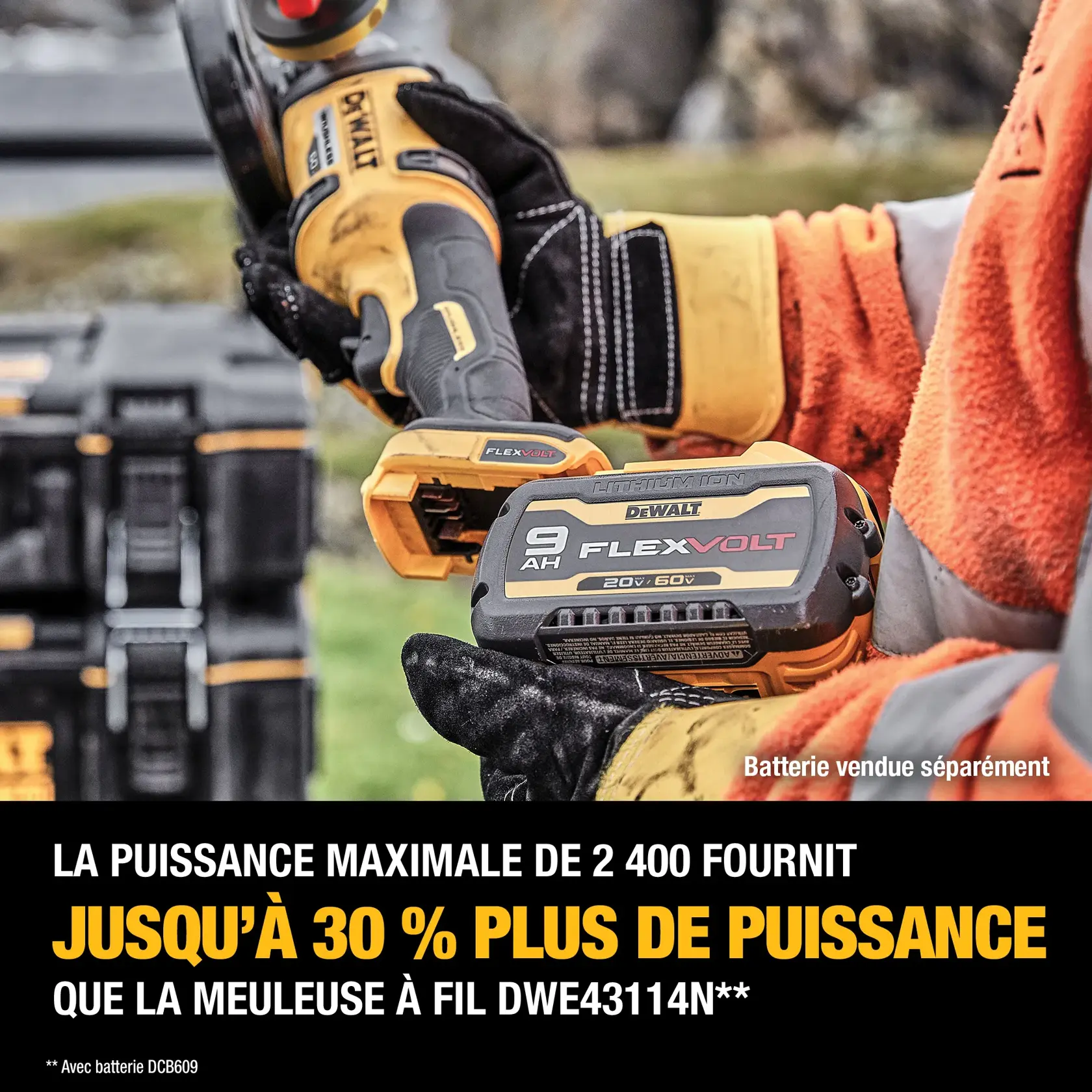 Close-up of a DEWALT FLEXVOLT 9Ah lithium-ion battery being held by a person wearing gloves and an orange jacket. The battery is being installed in a DEWALT power tool, with tool cases visible in the background. Text on the image highlights that 2,400 MWO provides up to 30% more power than a corded DWE43114N grinder, with a note stating the battery is sold separately.