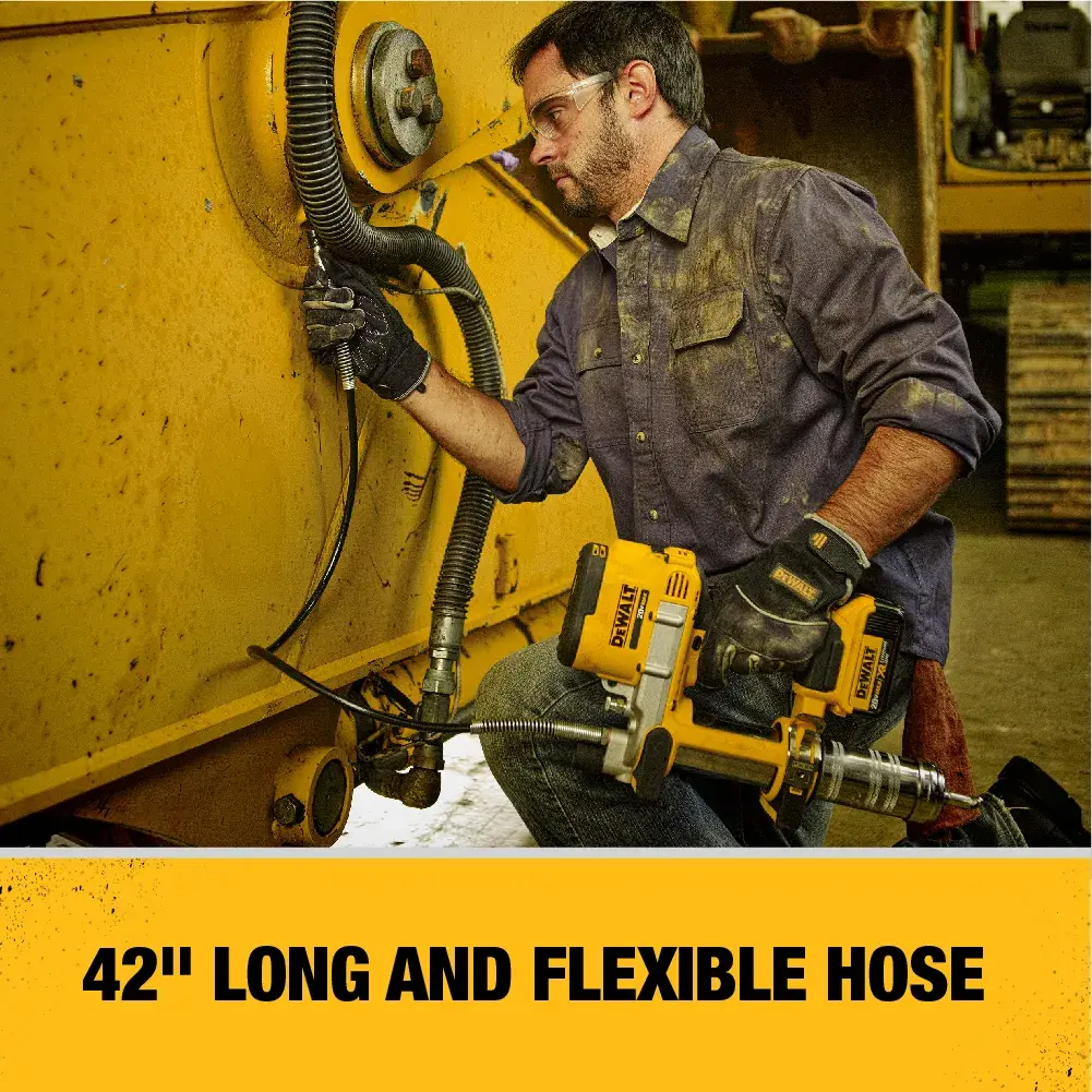 A person is using a DEWALT DCGG571M1 grease gun with a 42-inch long and flexible hose to lubricate a large yellow industrial machine. The person's face is blurred for privacy and the image highlights the tool's hose length and flexibility.