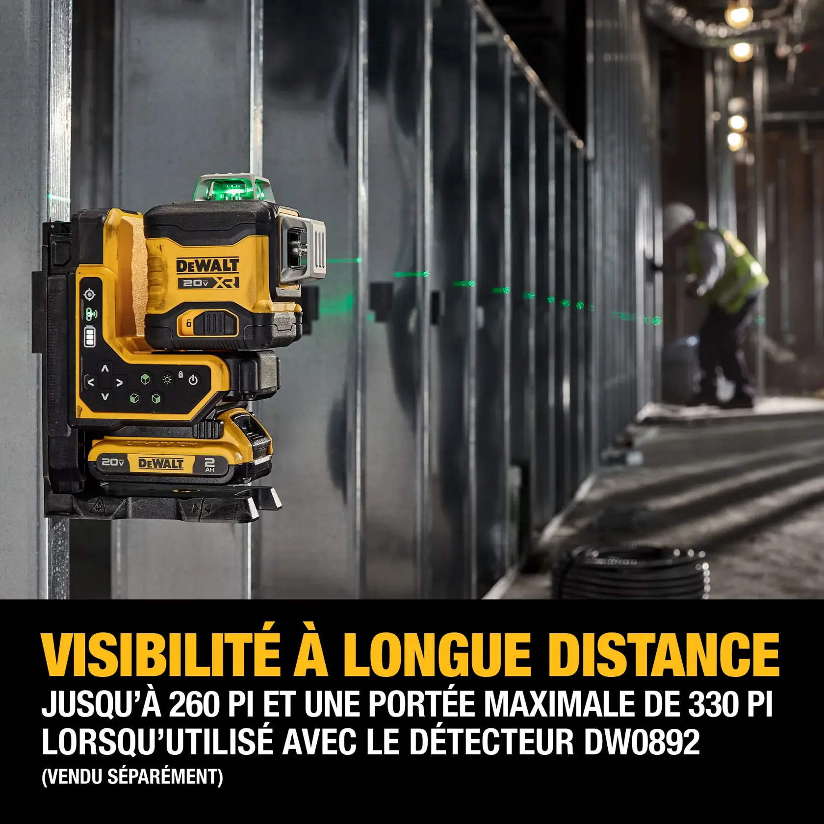 A DEWALT 20V XR green laser level is mounted on a metal frame inside a construction site. The device projects a long, visible green laser line across the room. Text on the image highlights long-range visibility, reaching up to 260 feet and a maximum of 330 feet with the DW0892 detector, which is sold separately.