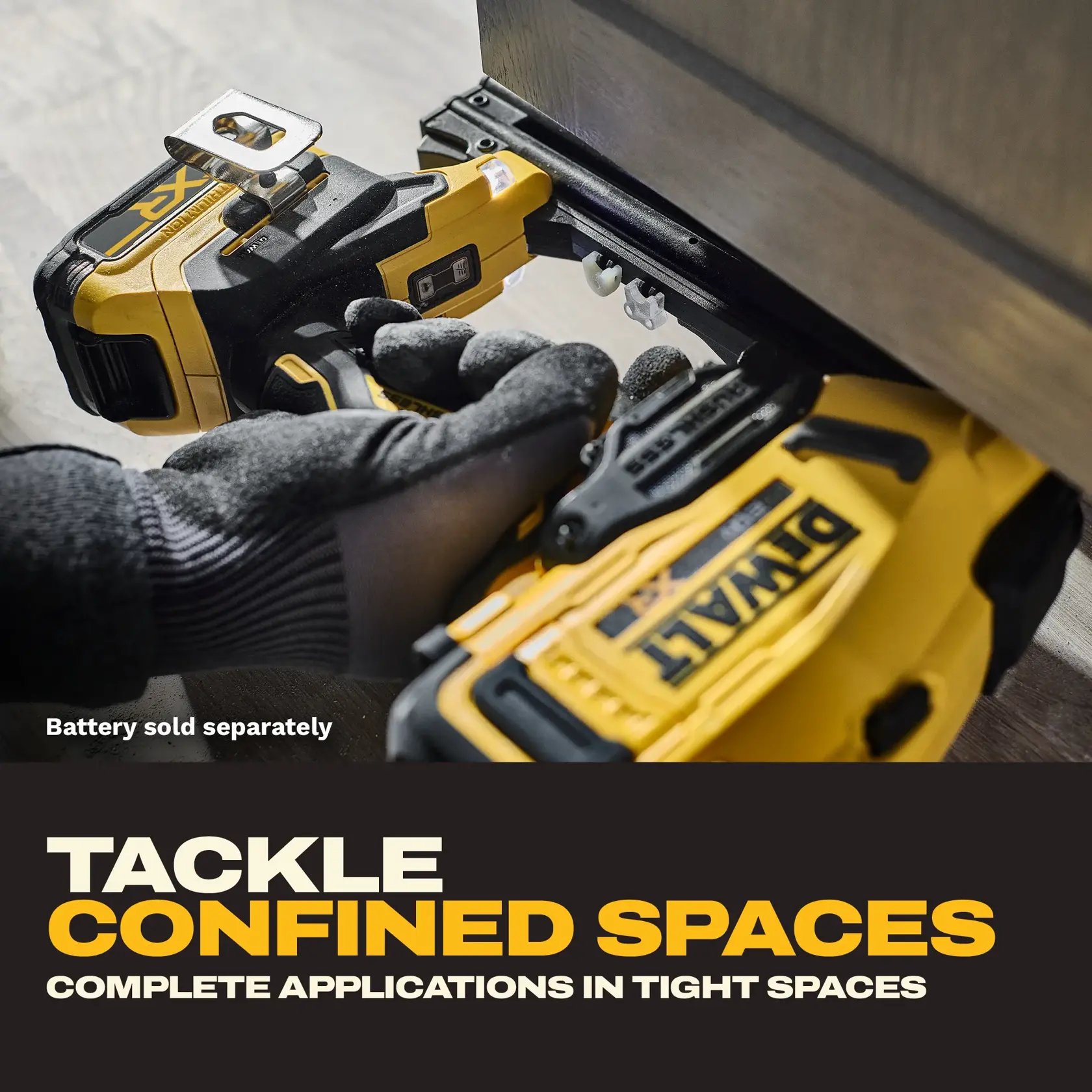A person wearing work gloves uses a DEWALT cordless nail gun model DCN210B in a tight space under a piece of furniture. The slogan 'Tackle confined spaces - Complete applications in tight spaces' is shown, with a note that the battery is sold separately.