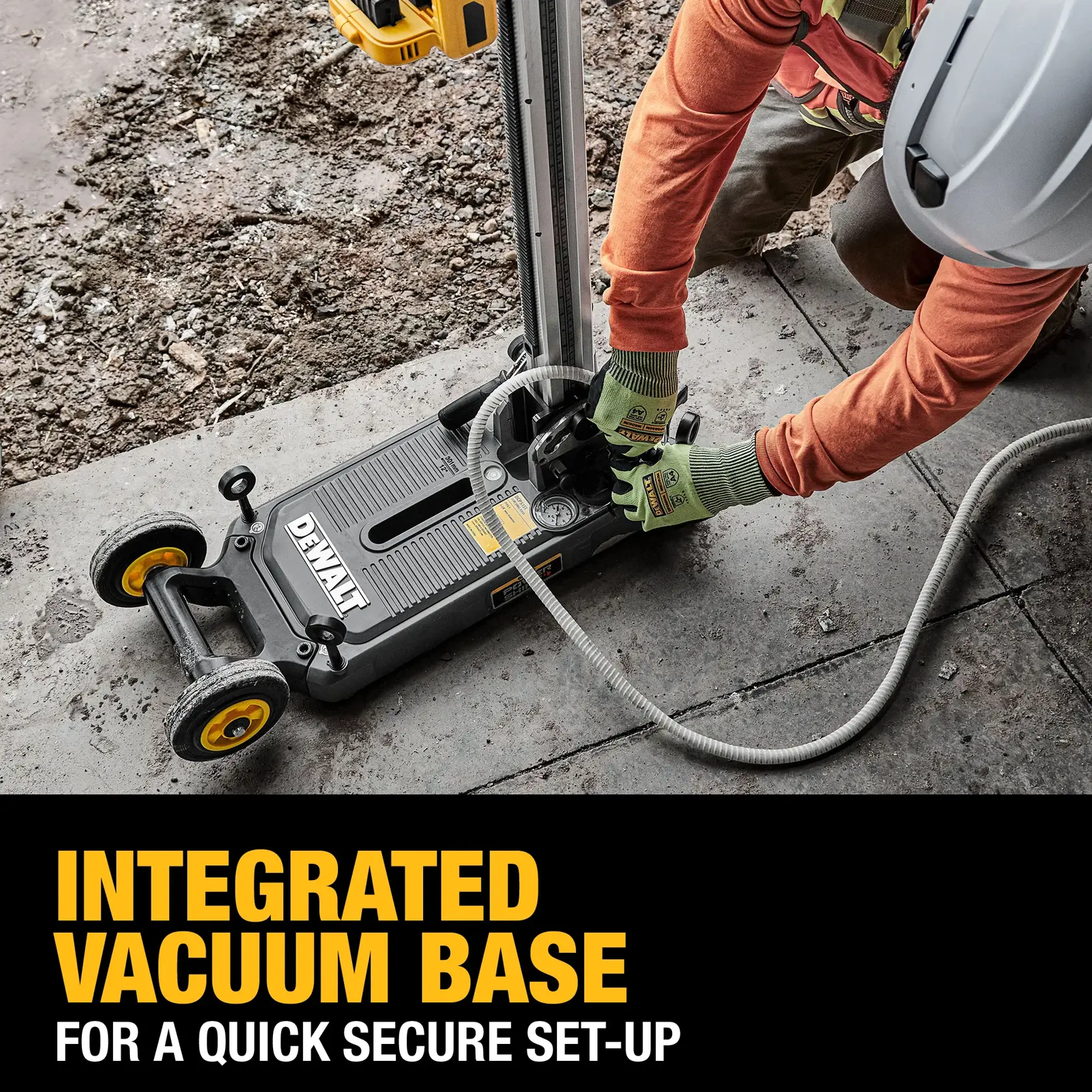A DEWALT power tool with an integrated vacuum base is being set up by a worker wearing gloves and a safety helmet on a concrete surface. The tool features yellow wheels and is connected to a hose. Text on the image reads 'Integrated vacuum base for a quick secure set-up.'