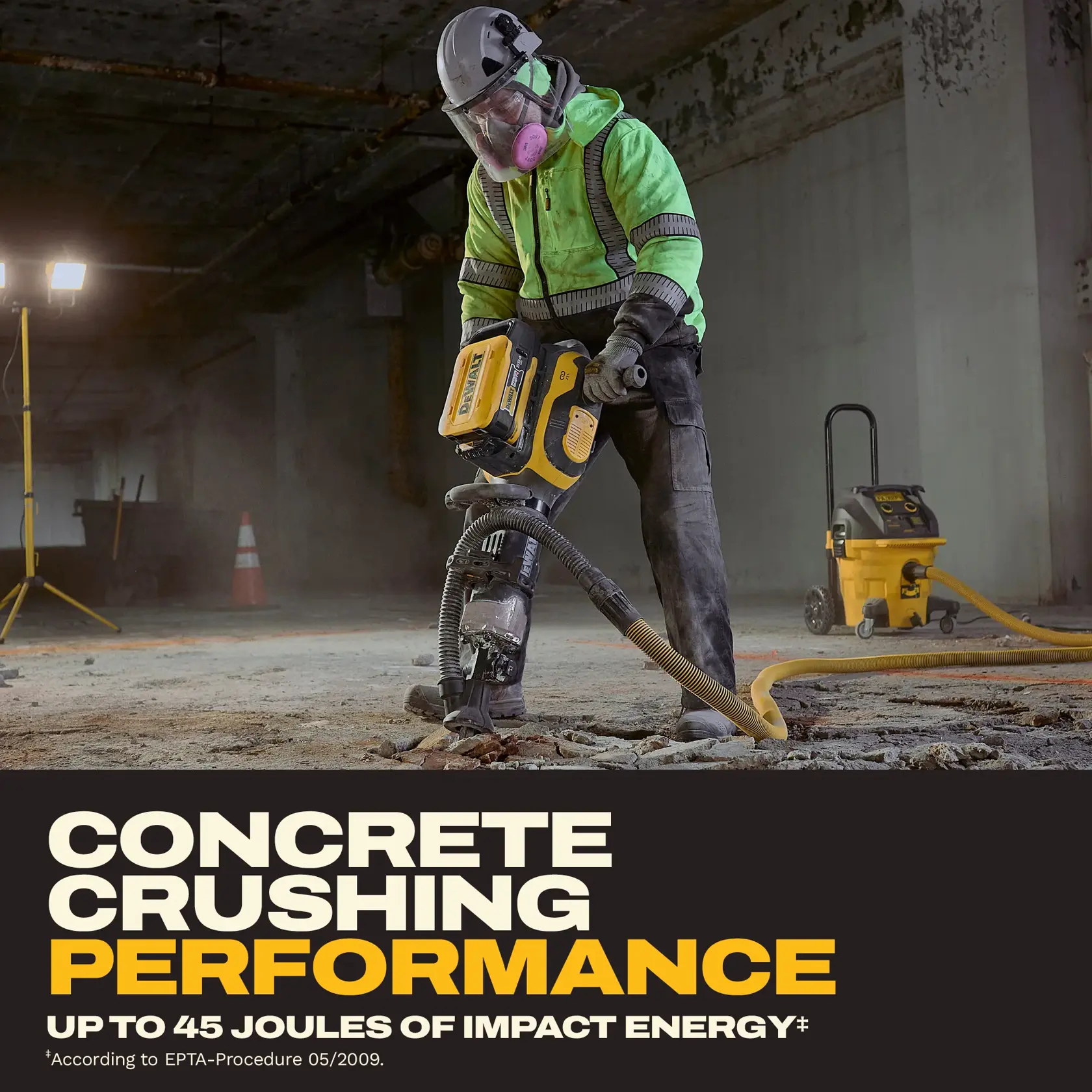 Worker in safety gear uses a DEWALT jackhammer to break concrete in an industrial setting.