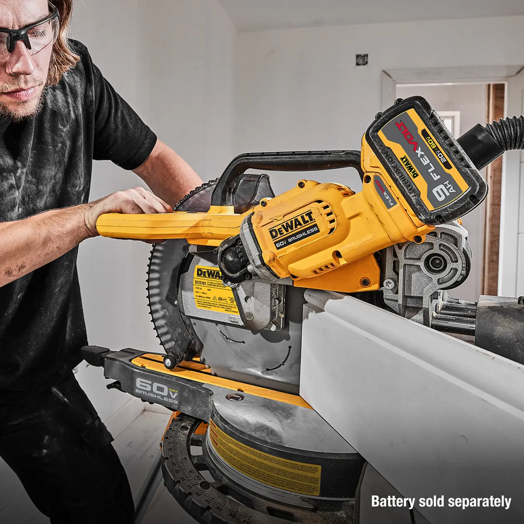 A person using a DEWALT 60V brushless miter saw to cut a piece of white trim, with a large FlexVolt battery attached. The text on the image reads, 'Battery sold separately.'