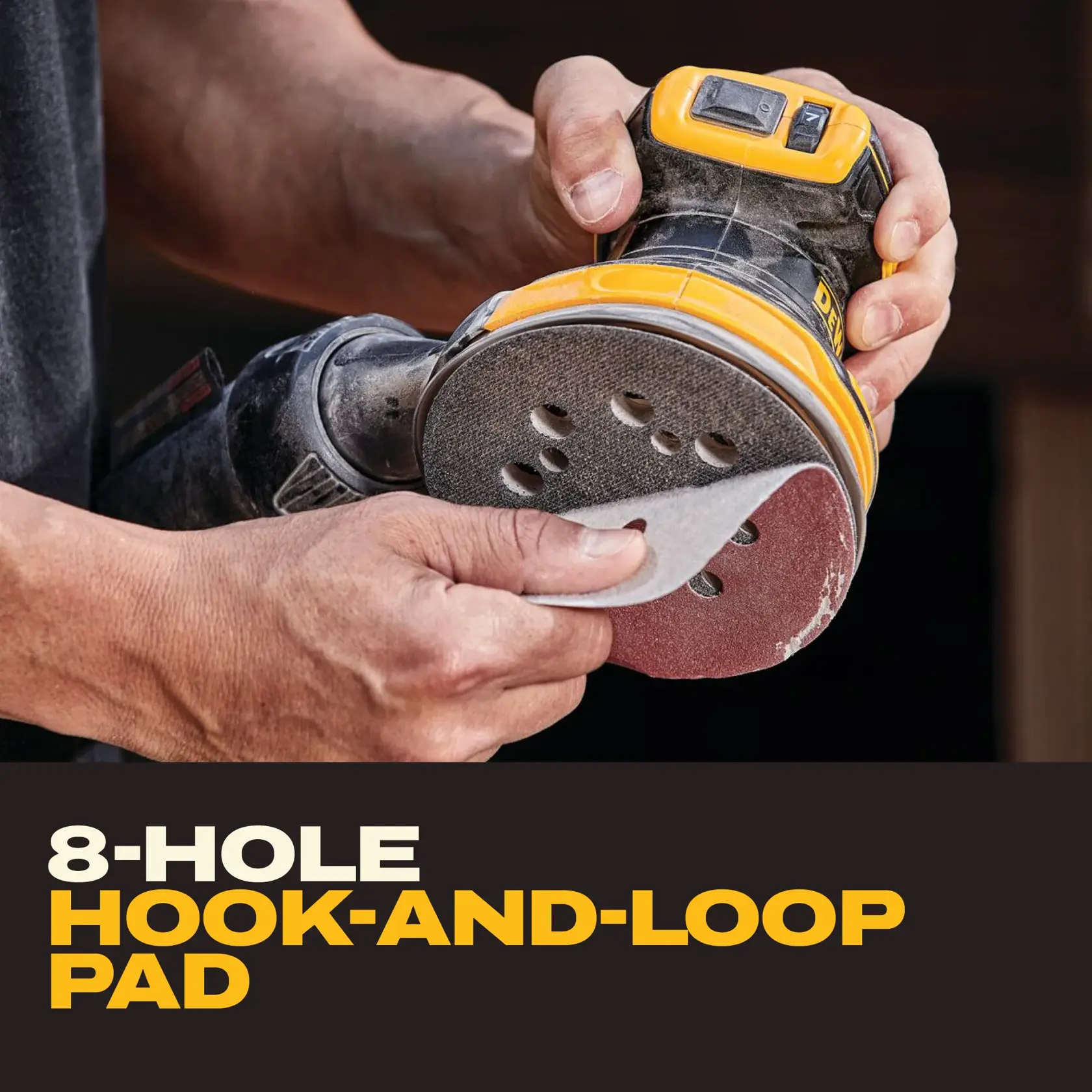 Person attaching sandpaper to an 8-hole hook-and-loop pad on a DEWALT sander.