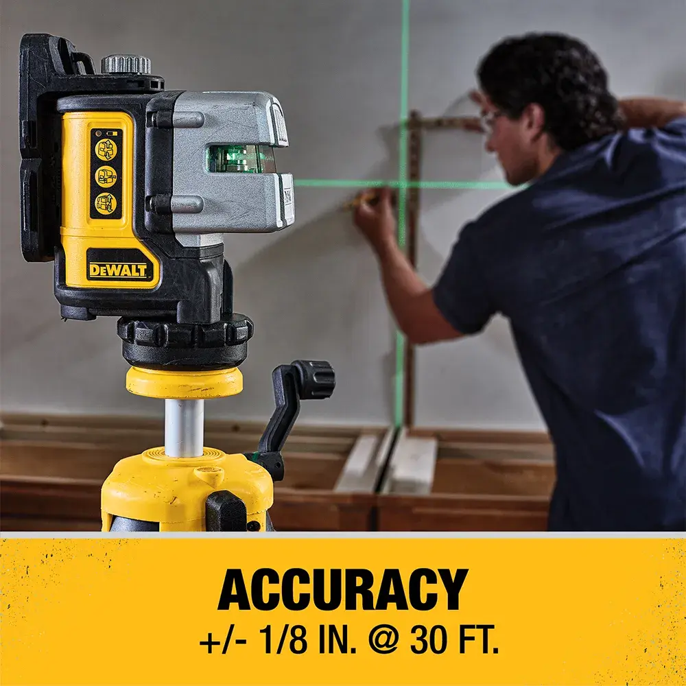 A DEWALT green cross-line laser level is set up on a yellow tripod. A person is using the laser to align objects on a wall. The text below the image highlights the accuracy: '+/- 1/8 inch at 30 feet.'