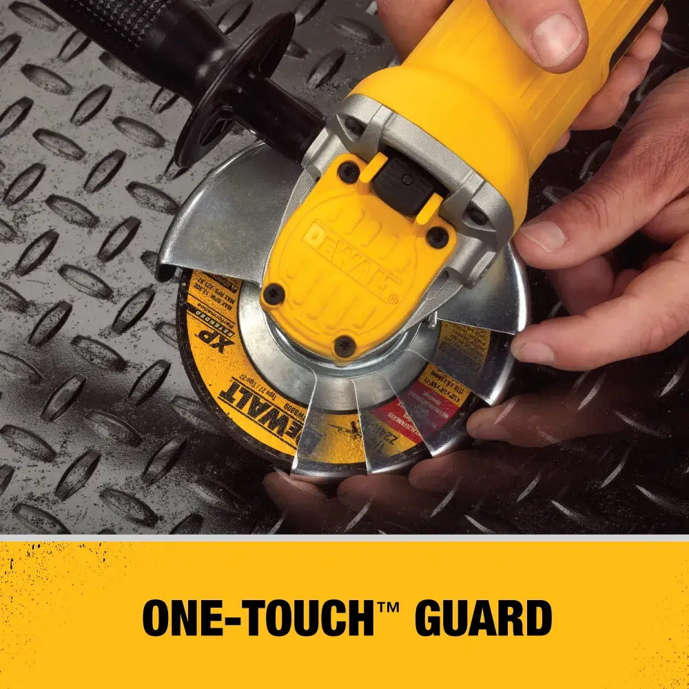 A close-up of a DEWALT DWE4120 angle grinder being adjusted by a person, showing the One-Touch guard feature over a metallic diamond plate surface.