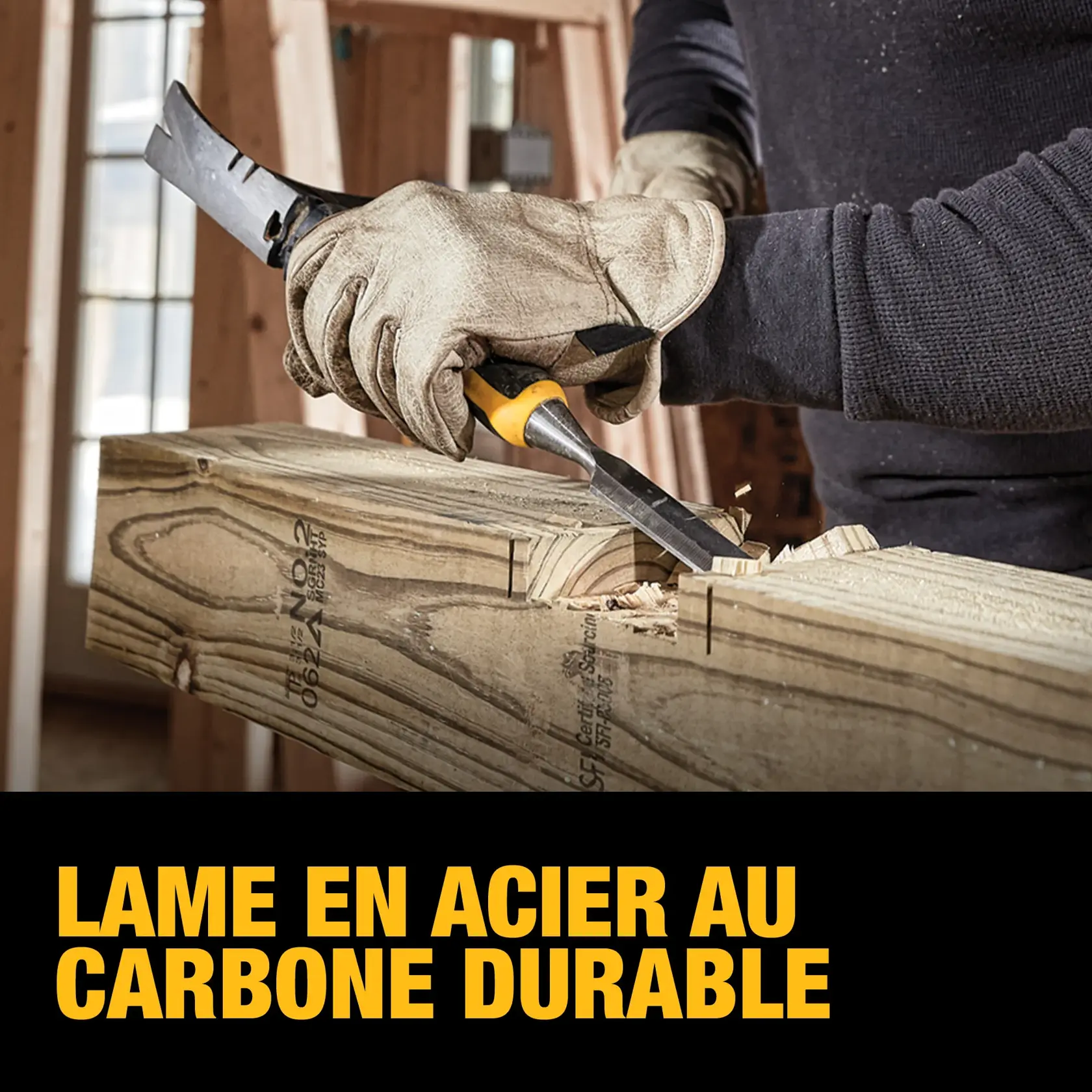 A person wearing work gloves uses a DEWALT carbon-steel blade chisel to carve wood at a construction site. The wooden beam is being shaped, and the image highlights the durability of the carbon-steel blade.