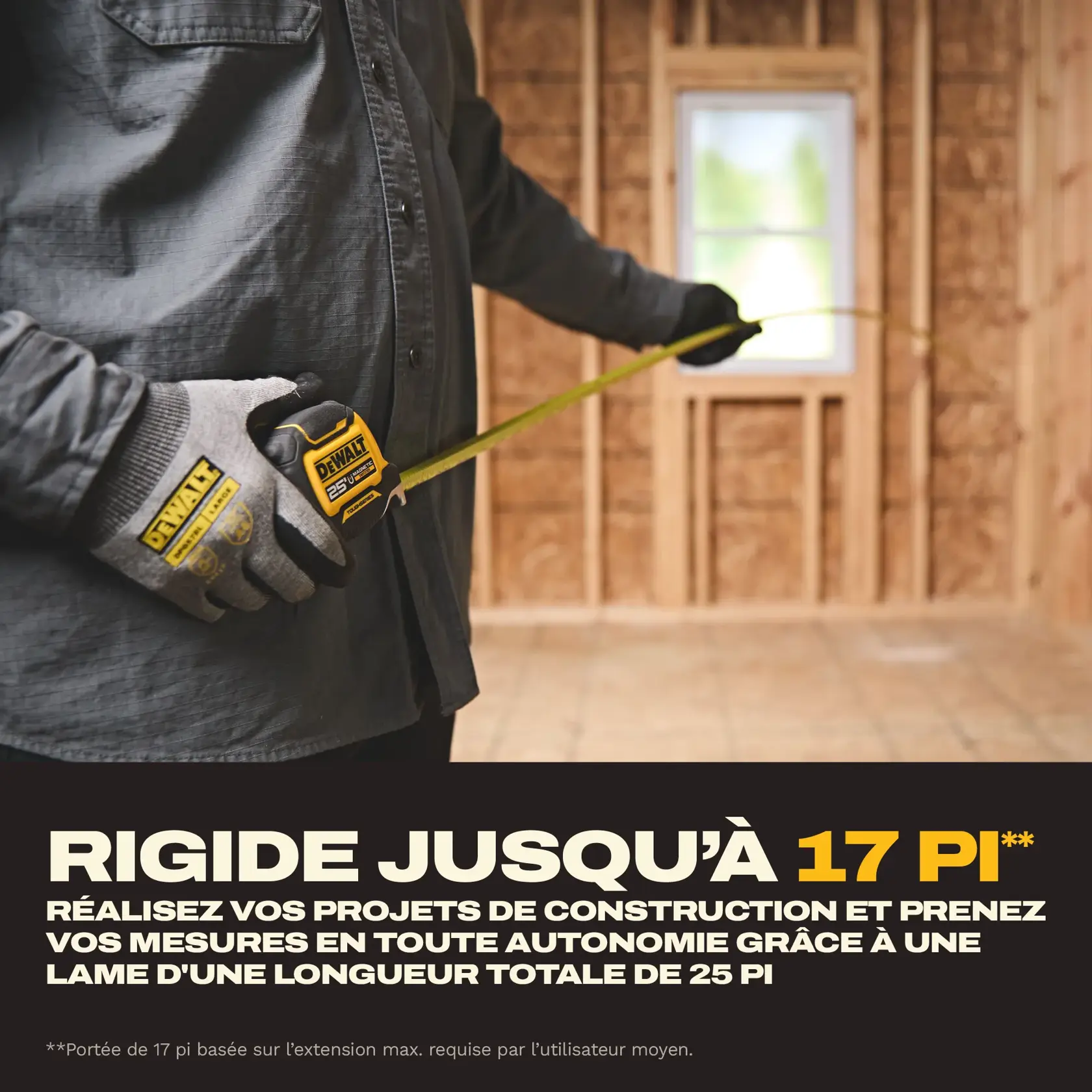 A person wearing work gloves is using a DEWALT 25 ft tape measure inside a partially constructed wooden room. The tape measure is extended, and the text highlights a 17 ft max reach for large-scale construction projects with 25 ft of total blade length.