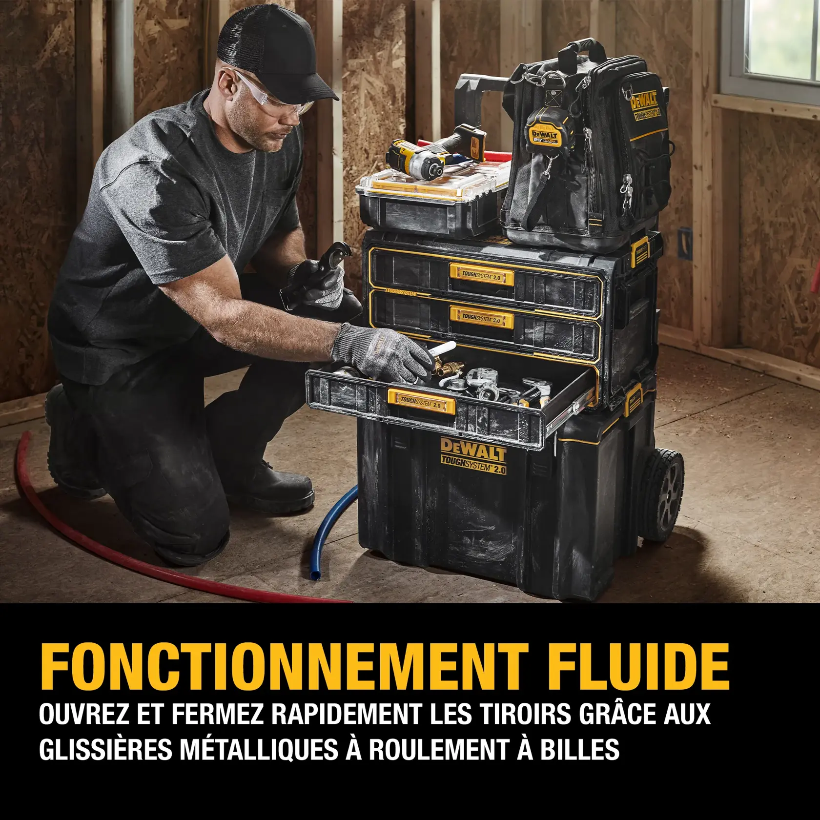 A person wearing work gloves is organizing tools and accessories in a DEWALT ToughSystem 2.0 storage system with three shallow drawers and a clear-lid top compartment, placed on a workbench in a workshop setting. The bottom of the image features French text promoting large storage space and the shallow drawers for tool organization on demanding job sites.