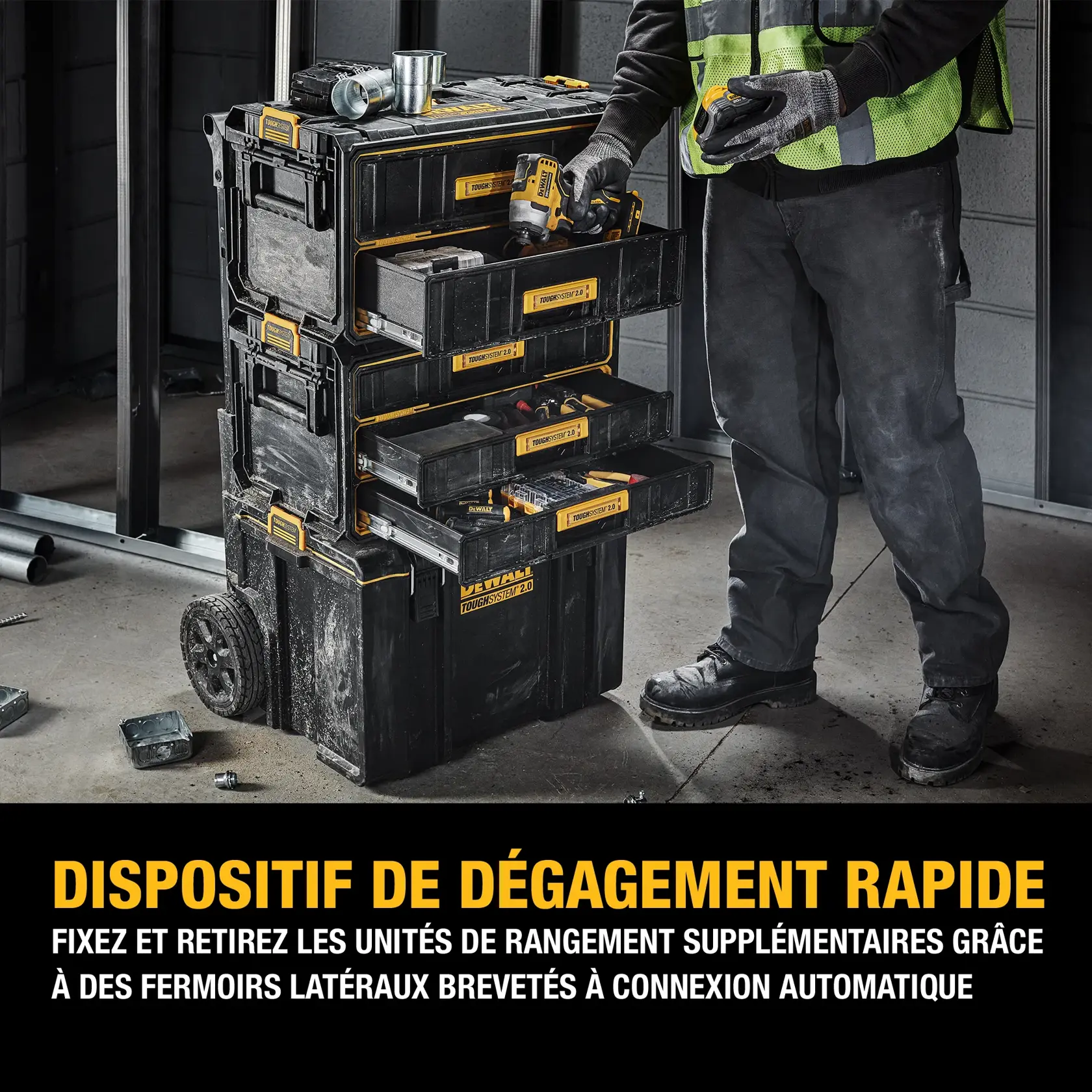 A person uses a DEWALT ToughSystem 2.0 storage unit with three shallow drawers and an open top compartment, organizing tools and accessories on a workbench in a workshop.