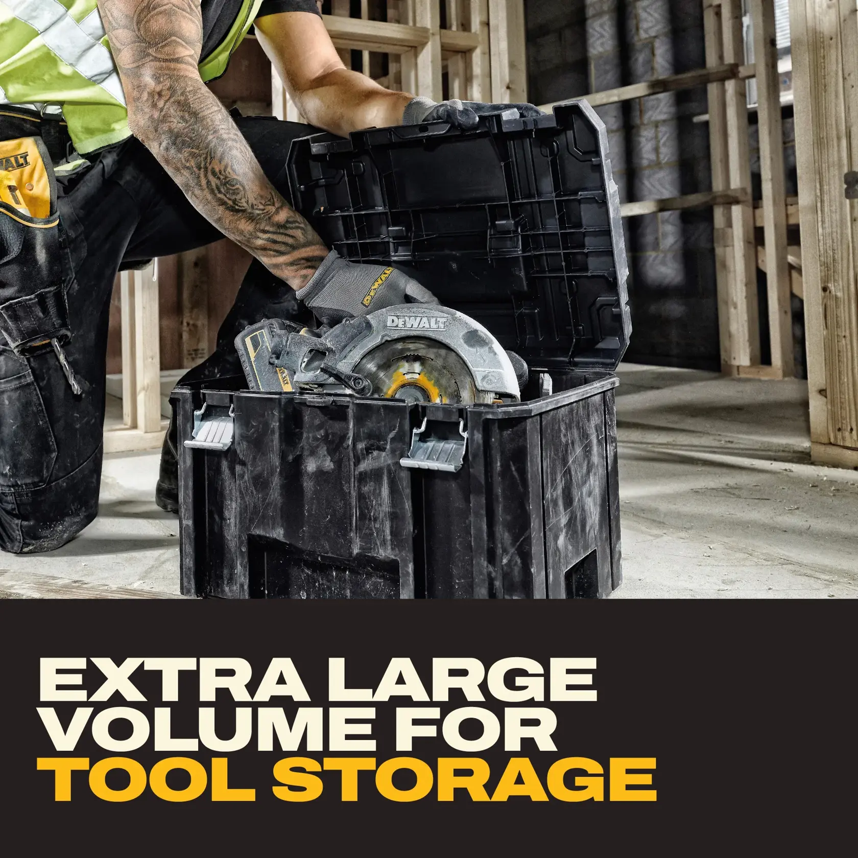 A person wearing work gloves and a safety vest places a DEWALT circular saw into a large black tool storage box. The scene is set at a construction site, and the text below reads 'Extra large volume for tool storage.'