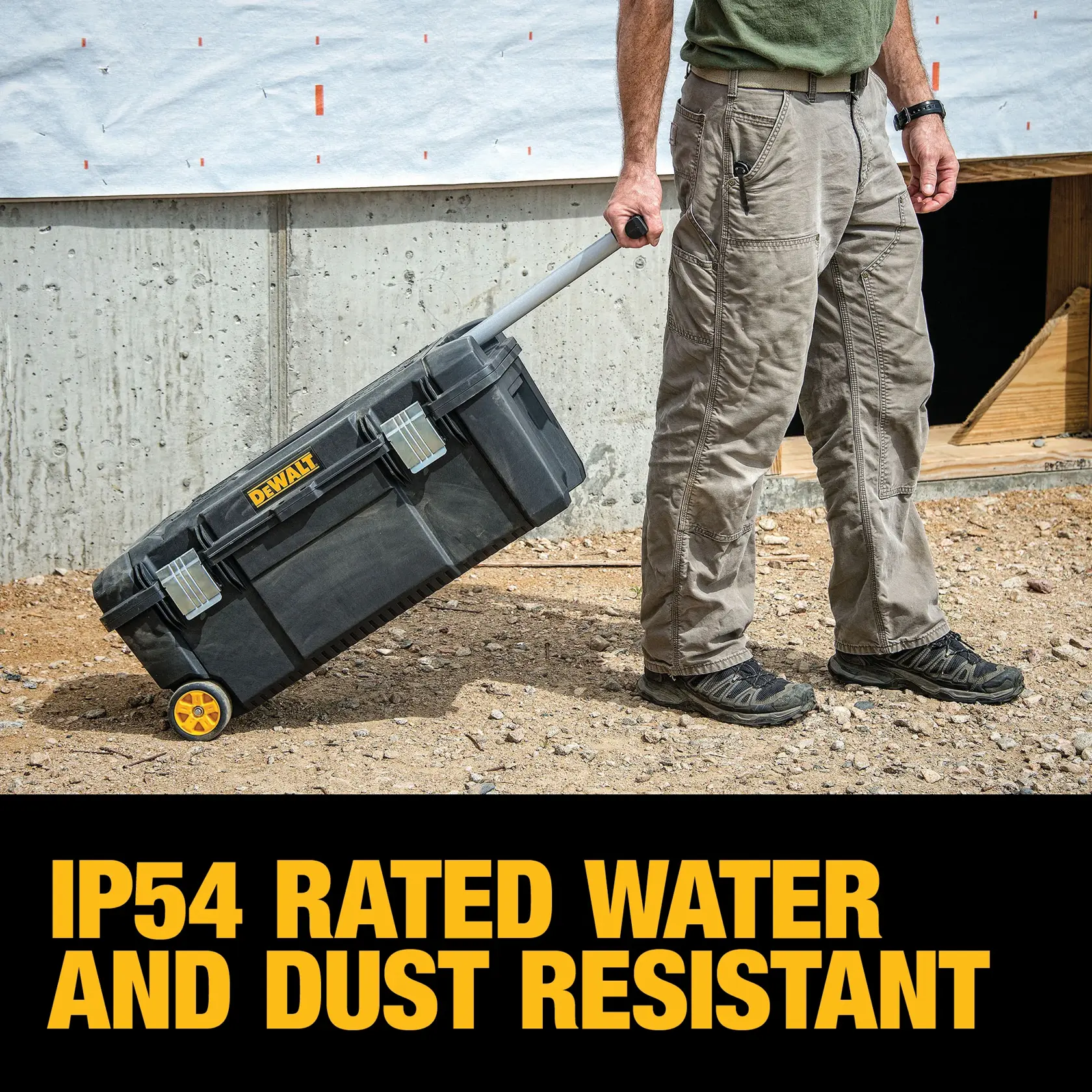 A person is pulling a DEWALT wheeled tool box on a construction site. The tool box is black with yellow accents and the text below reads 'IP54 rated water and dust resistant' in bold yellow letters.