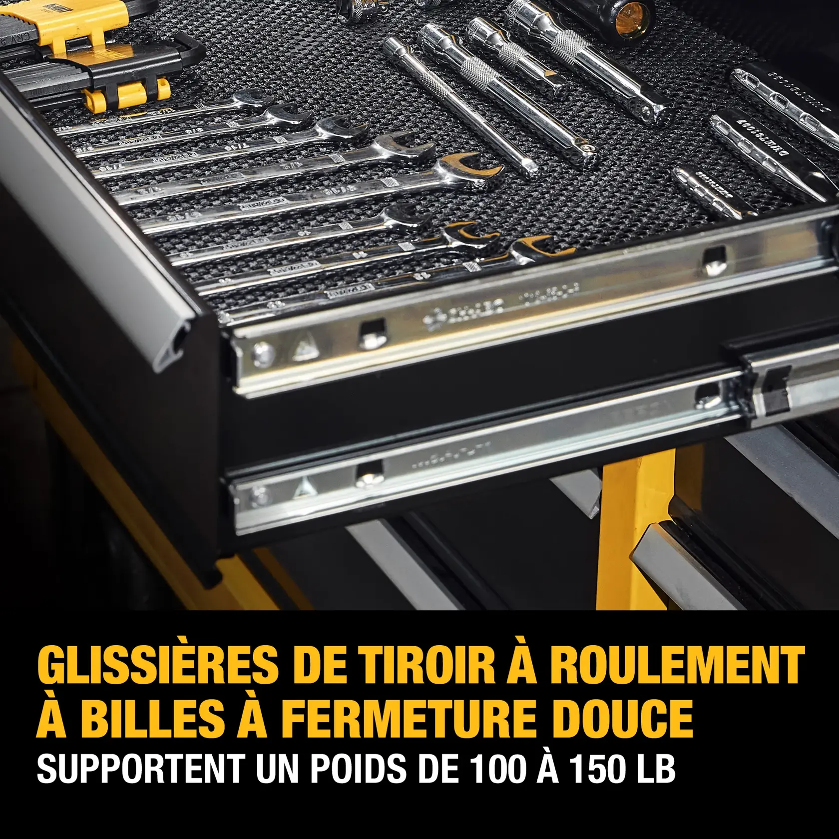 A close-up image of an open tool drawer with various metal wrenches and tools organized inside. The drawer has soft close, ball-bearing slides that can support 100-150 pounds, as indicated by the bold yellow and white text on the lower part of the image.