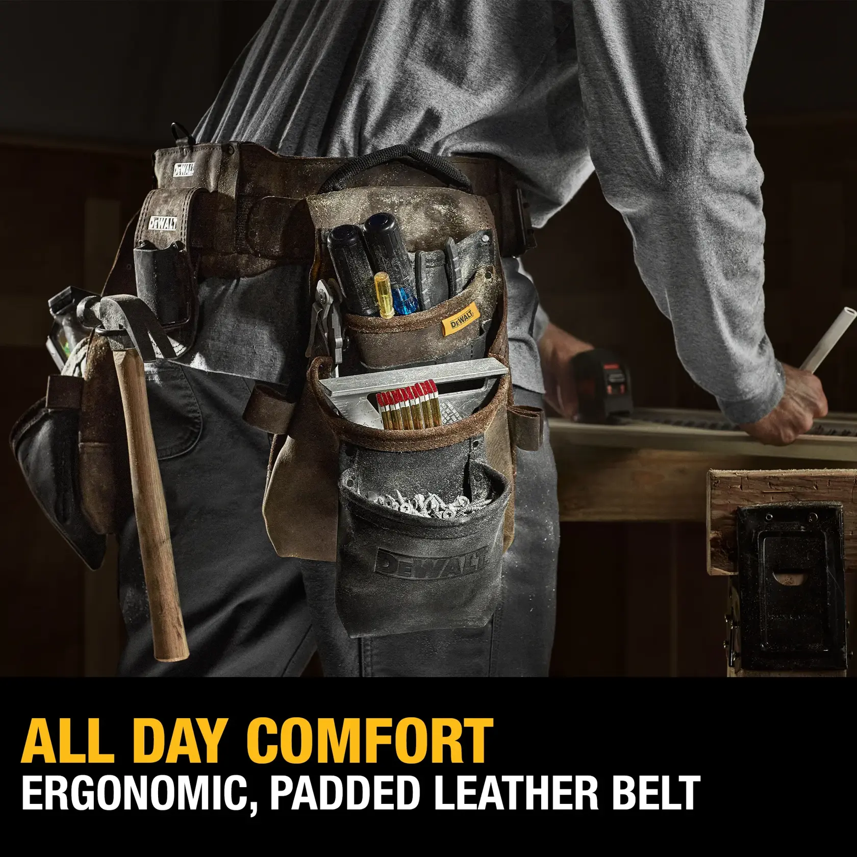 A person wearing a DEWALT ergonomic, padded leather tool belt filled with various tools and accessories, standing at a workbench. Text on the image reads: 'ALL DAY COMFORT - ERGONOMIC, PADDED LEATHER BELT.'