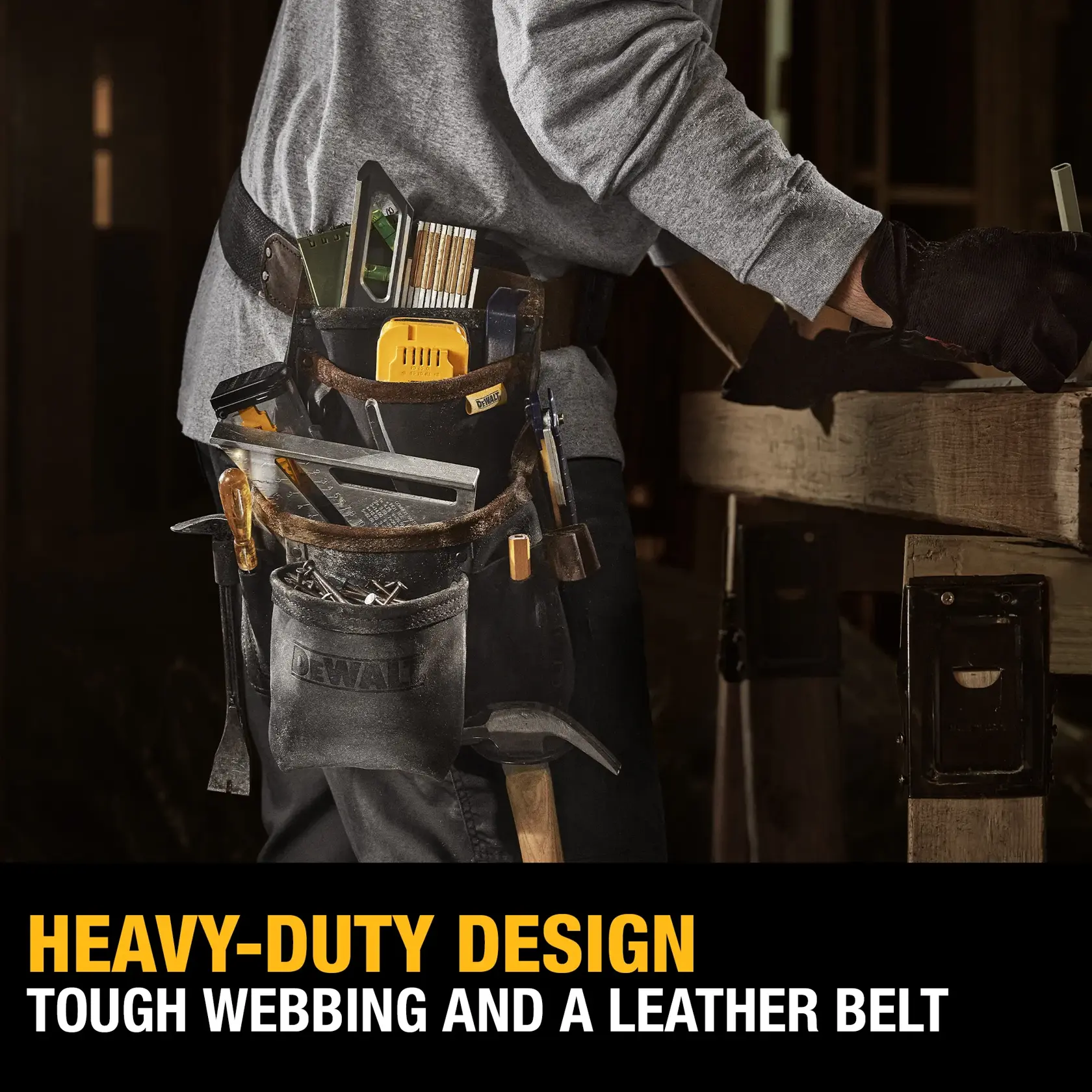 A person wearing a DEWALT heavy-duty tool belt with tough webbing and a leather belt. The belt is loaded with various tools including a square, screwdriver, measuring tape, pencils, and other construction items. The person is working at a wooden table. The text at the bottom reads: 'HEAVY-DUTY DESIGN, TOUGH WEBBING AND A LEATHER BELT.'
