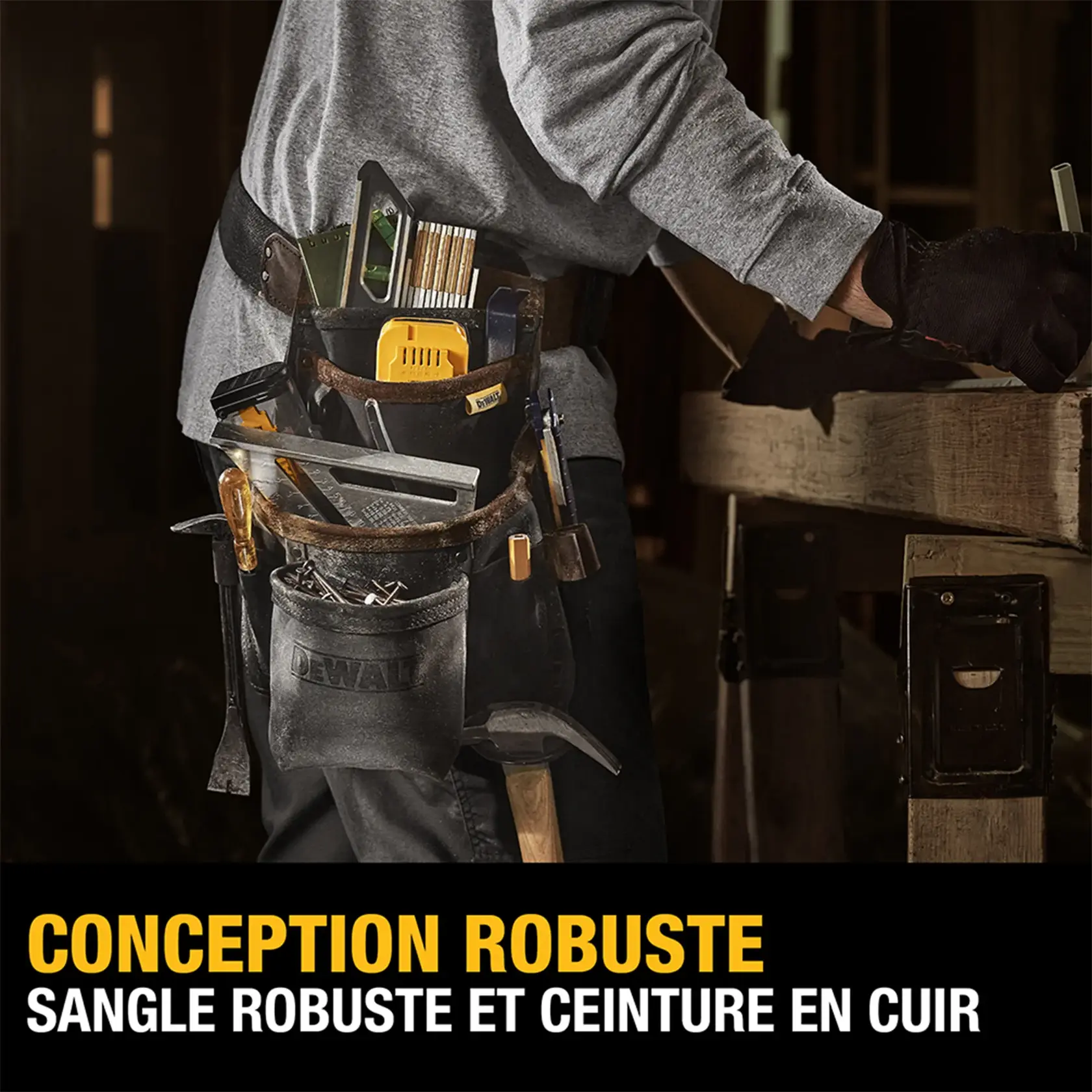 A person wearing a DEWALT heavy-duty tool belt with tough webbing and a leather belt. The belt is loaded with various tools including a square, screwdriver, measuring tape, pencils, and other construction items. The person is working at a wooden table. The text at the bottom reads: 'HEAVY-DUTY DESIGN, TOUGH WEBBING AND A LEATHER BELT.'