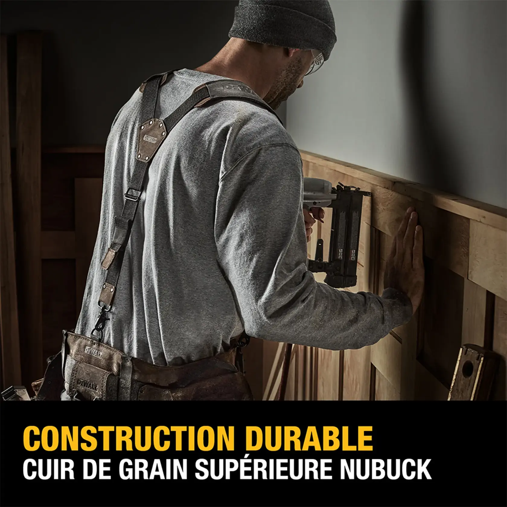 A person wearing a DEWALT work apron is using a power tool to work on a wooden wall. The apron is made of premium nubuck top-grain leather. Text reads: 'Durable Construction. Premium Nubuck Top-Grain Leather.'