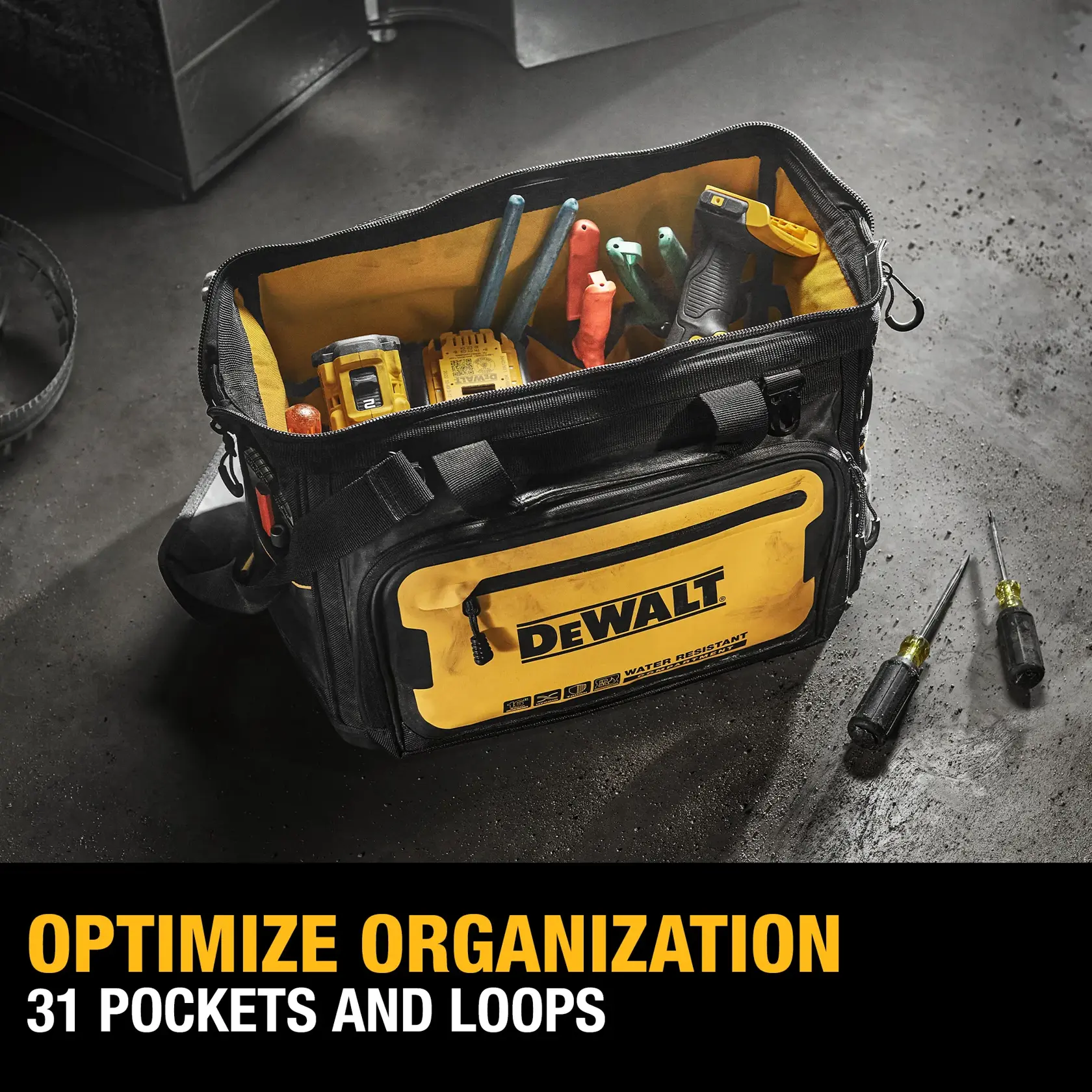 A DEWALT branded tool bag on a workshop floor, filled with various tools. The bag has a yellow front pocket and is designed with 31 pockets and loops for optimal organization. Two screwdrivers are placed beside the bag. The text 'OPTIMIZE ORGANIZATION 31 POCKETS AND LOOPS' is visible at the bottom.