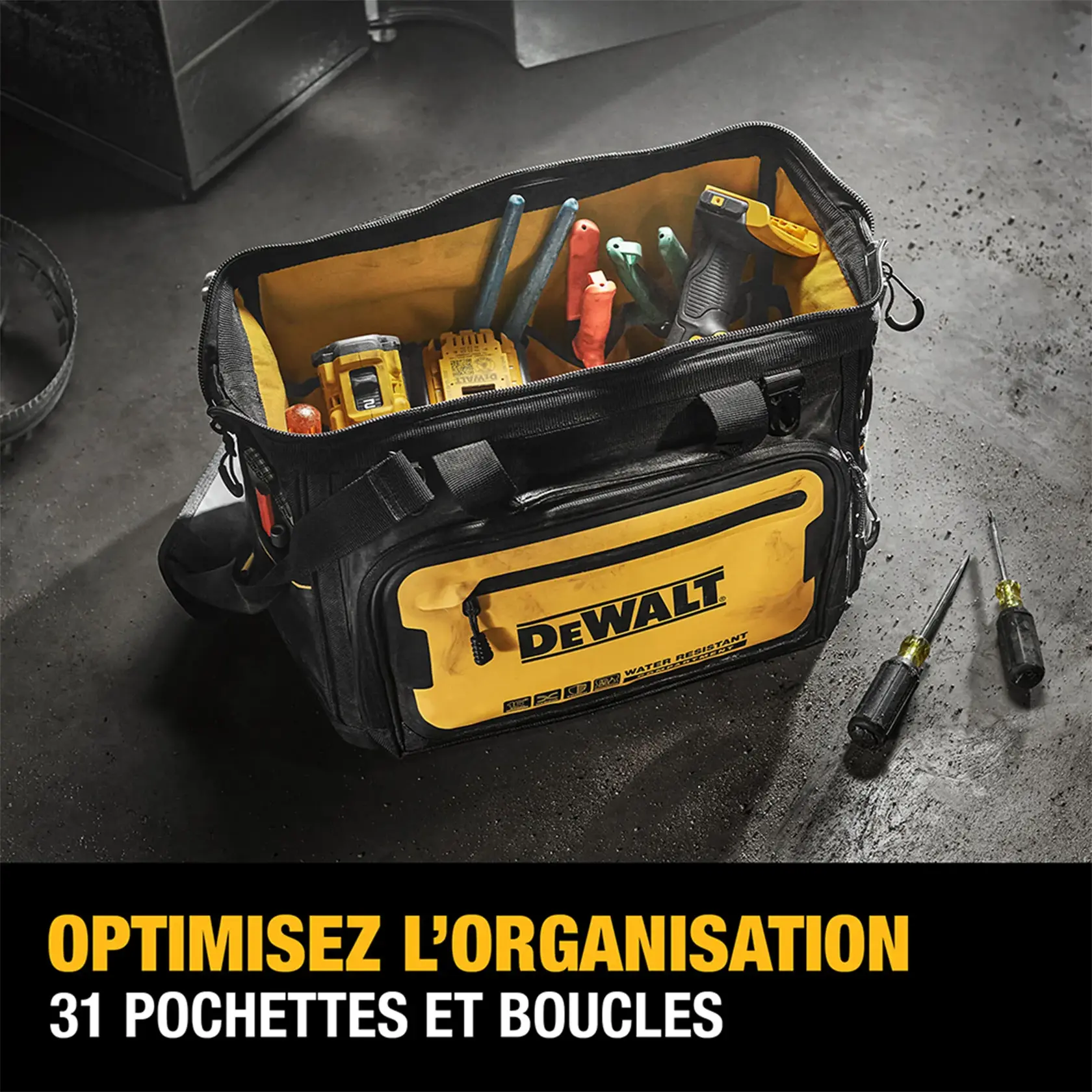 A DEWALT branded tool bag on a workshop floor, filled with various tools. The bag has a yellow front pocket and is designed with 31 pockets and loops for optimal organization. Two screwdrivers are placed beside the bag. The text 'OPTIMIZE ORGANIZATION 31 POCKETS AND LOOPS' is visible at the bottom.