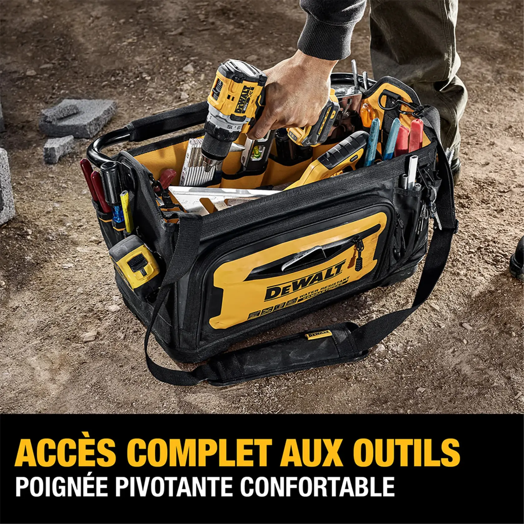 A DEWALT-branded tool bag on a worksite, filled with various hand tools and a power drill. A person's hand is reaching into the bag. The bag is designed for full access to tools and features a comfort-grip swivel handle. Text on the image reads: 'FULL ACCESS TO TOOLS, COMFORT-GRIP SWIVEL HANDLE.'