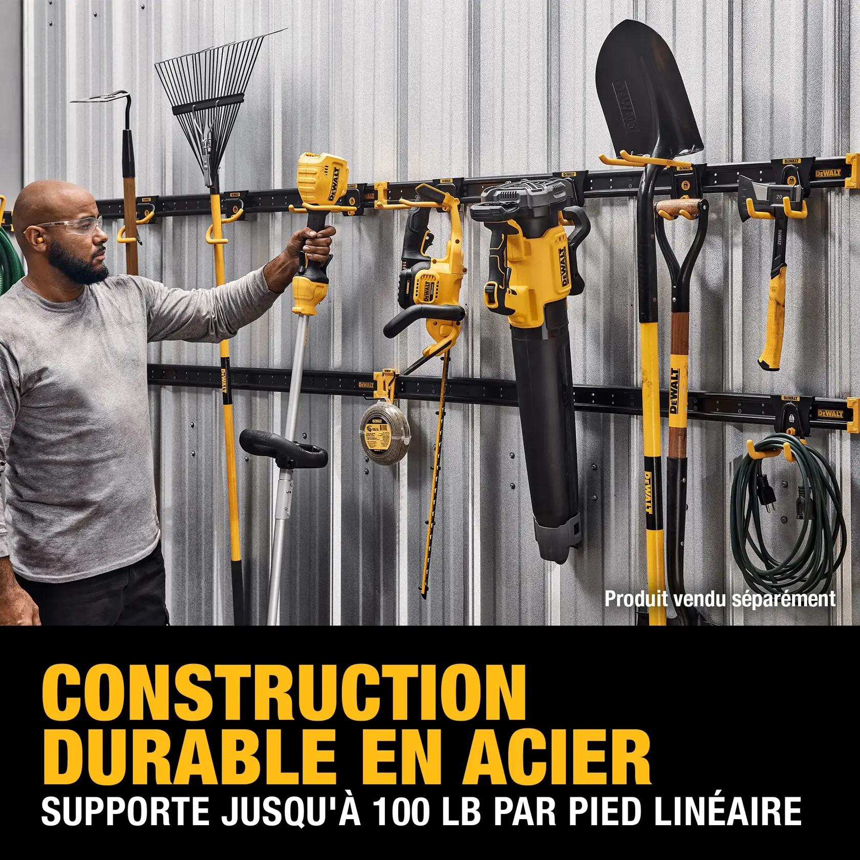 A person is organizing outdoor tools such as a shovel, rake, trimmer, leaf blower, and power tools on a DEWALT steel wall rack system attached to a metal shed wall. The system advertises durable steel construction and supports up to 100 lbs. per linear foot. Tools and accessories are sold separately.