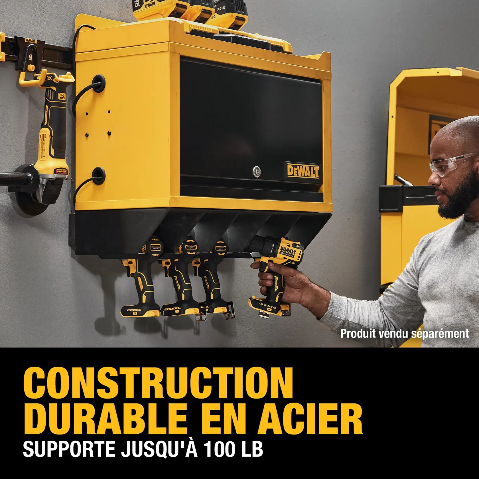 A DEWALT steel wall-mounted tool storage cabinet with several power tools organized below and on the sides. A person is grabbing a tool from the cabinet. Text on the image states: 'DURABLE STEEL CONSTRUCTION SUPPORTS UP TO 100 LBS.' and 'Product sold separately.'