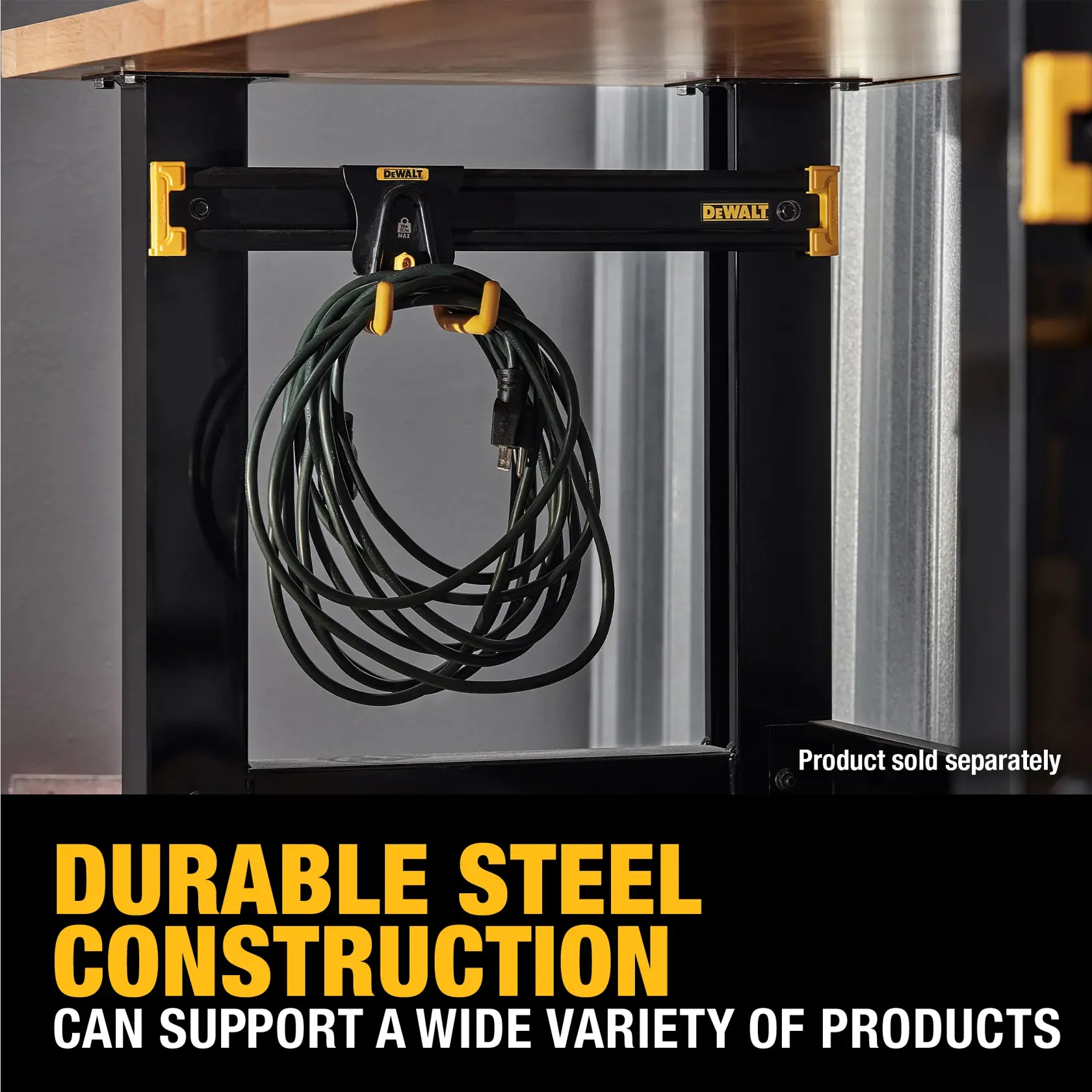 A DEWALT steel construction product is shown mounted under a wooden workbench, holding a coiled electrical cord. The product features yellow accents and the DEWALT logo, with text indicating its durable steel construction that can support a wide variety of products. A note states 'Product sold separately.'