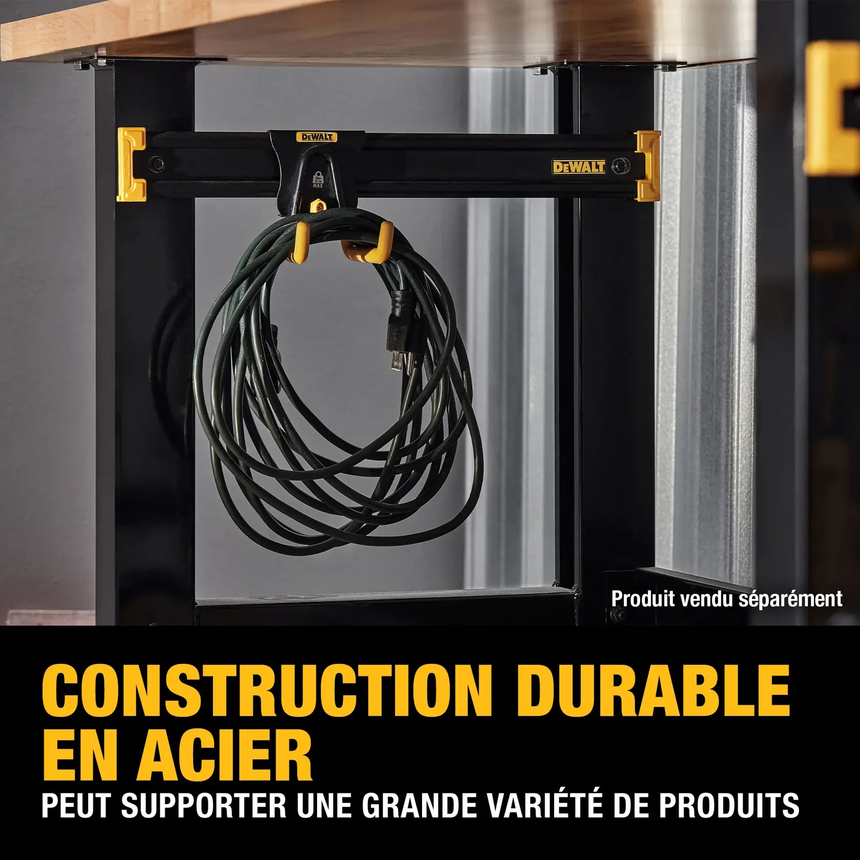 A DEWALT steel construction product is shown mounted under a wooden workbench, holding a coiled electrical cord. The product features yellow accents and the DEWALT logo, with text indicating its durable steel construction that can support a wide variety of products. A note states 'Product sold separately.'