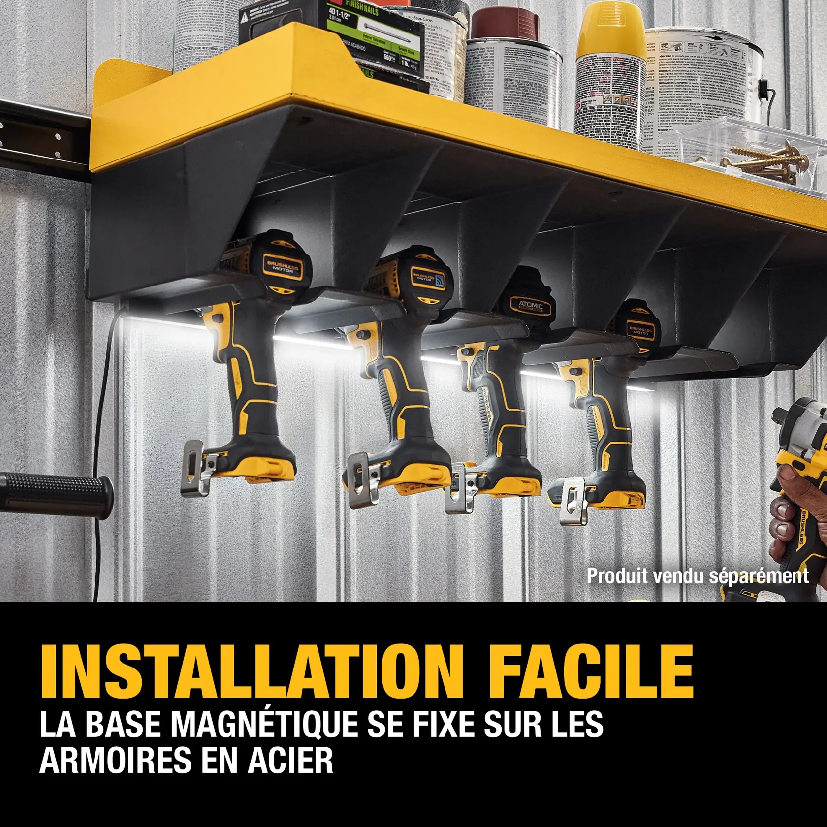 A yellow and black DEWALT magnetic base tool holder is mounted under a shelf in a workshop, holding four cordless drills, with cans and hardware stored on the shelf above. Text reads: 'Quick Installation: Magnetic base attaches to steel cabinets.'