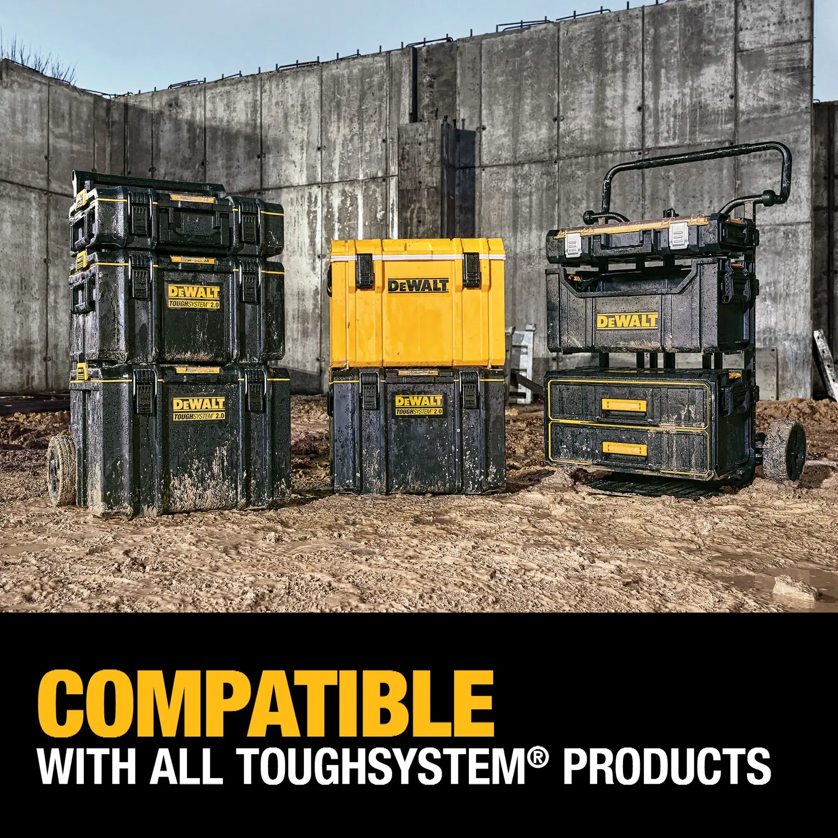 Three DEWALT ToughSystem storage products, including stackable toolboxes, a yellow storage case, and a wheeled cart with drawers, are shown on a muddy construction site with a concrete wall in the background. The text reads: 'COMPATIBLE WITH ALL TOUGHSYSTEM PRODUCTS.'