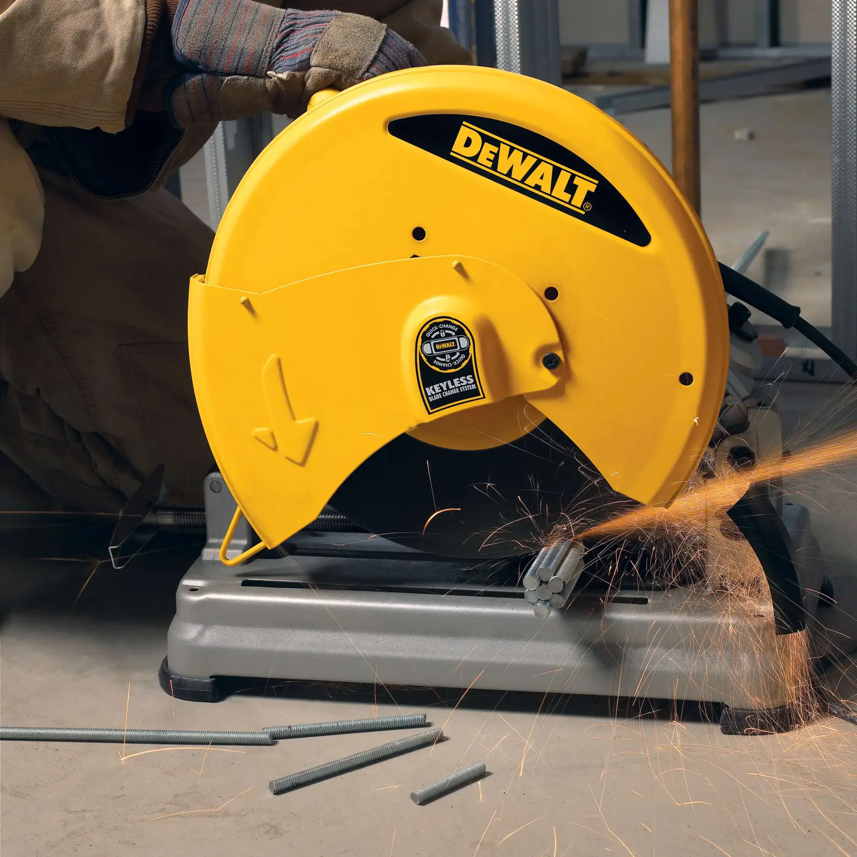 A DEWALT D28715 yellow metal cut-off saw in use, cutting metal rods and producing sparks, operated by a person wearing protective gloves.