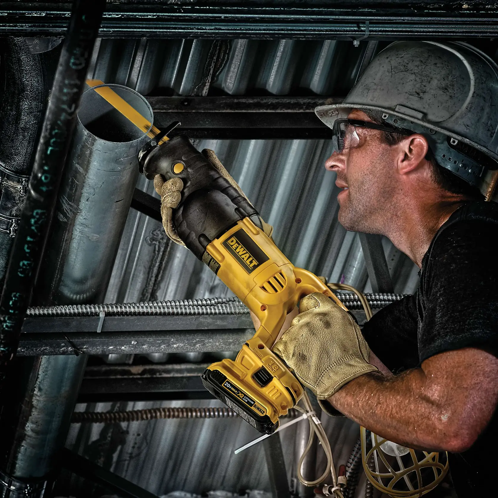 A person wearing gloves and a hard hat is using a DEWALT cordless reciprocating saw to cut a metal pipe in an industrial setting. The person's face is blurred for privacy.