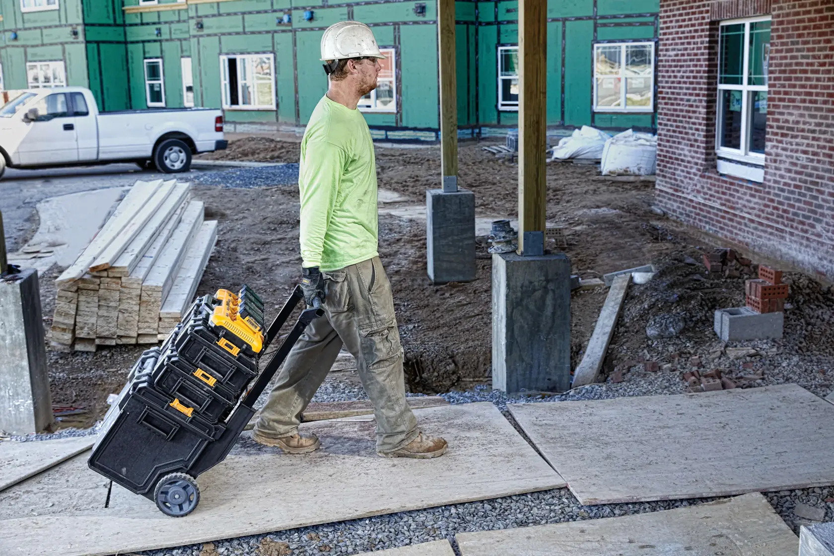 A DEWALT DCB104 charger with four batteries attached, displayed on a worktable with wooden planks in the background. The text reads 'Simultaneous 8 amp output per port for fast charging.'