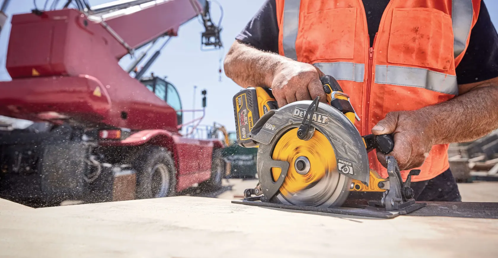 Worker using a DEWALT circular saw to cut wood at a construction site, wearing an orange safety vest.