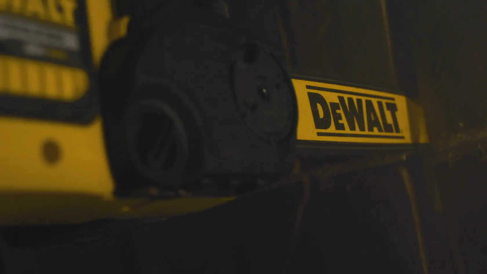 Close-up of a DEWALT power tool bar with yellow branding, partially visible in dim lighting.