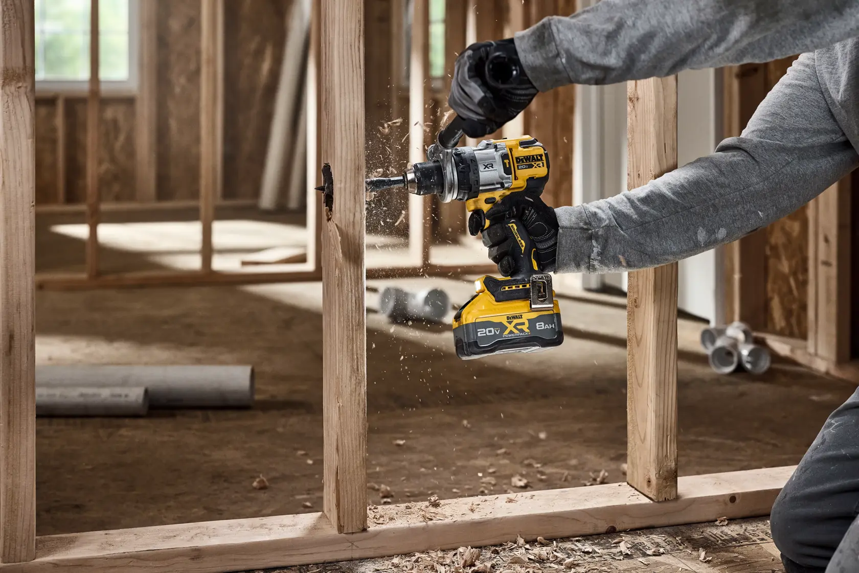 Person using DEWALT cordless drill to make a hole in a wooden frame during construction.