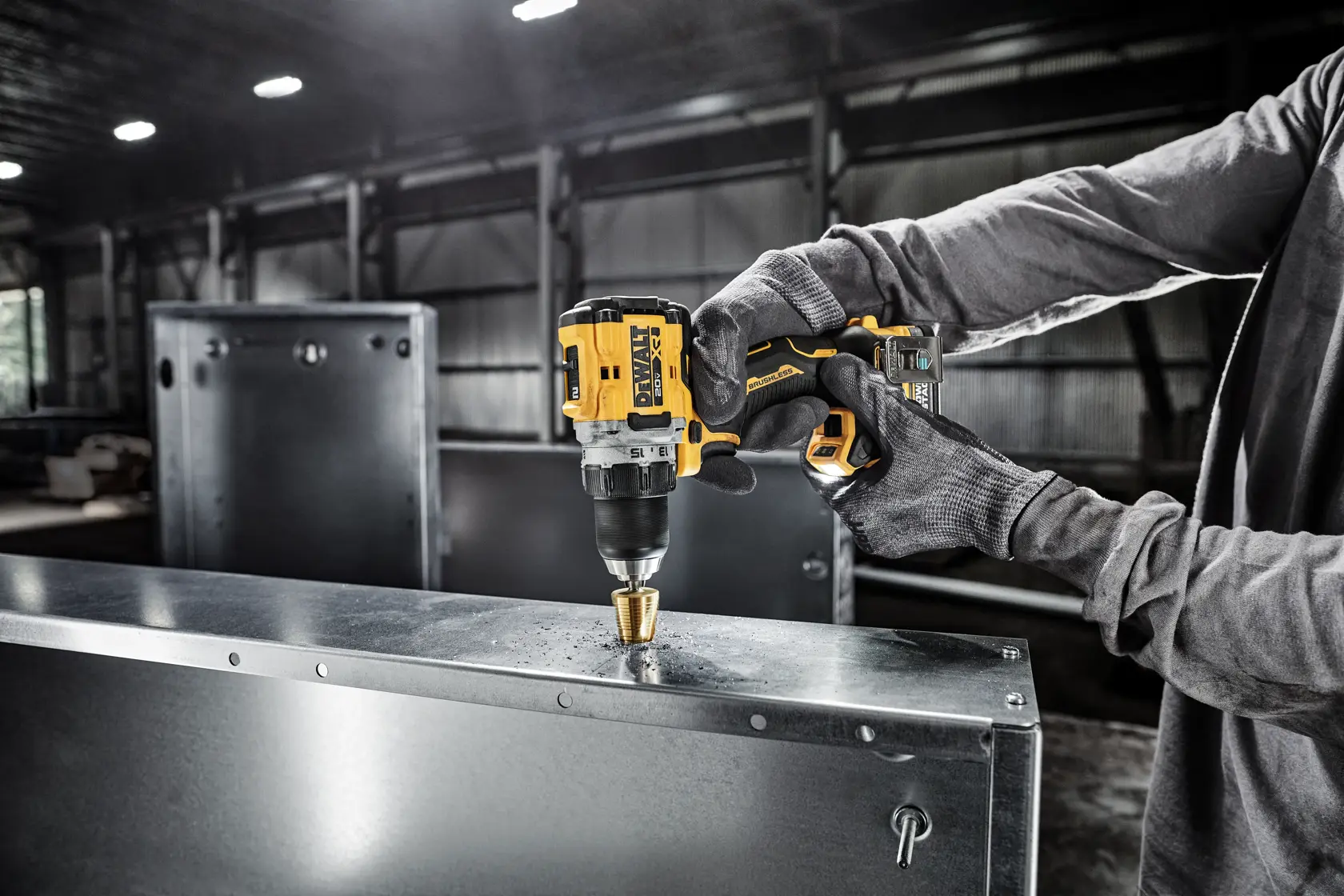 A person wearing gloves uses a DEWALT cordless drill to drill a hole in a metal sheet inside an industrial setting.