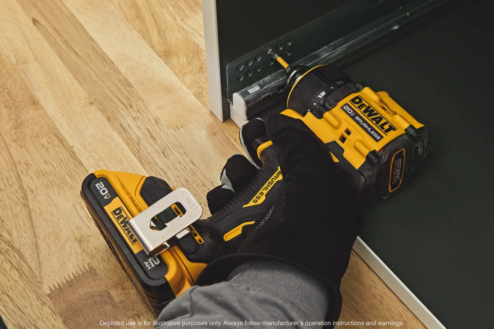 A person wearing a black glove is using a yellow and black DEWALT 20V cordless drill to screw into a metal rail attached to a piece of furniture on a wood floor.