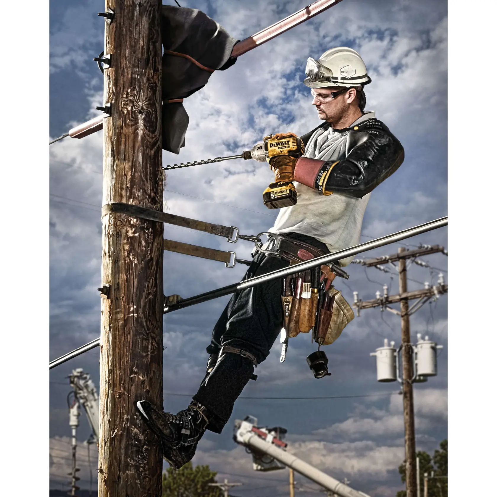 A utility worker wearing safety gear is climbing and working on a wooden utility pole using a DEWALT cordless power tool, with a cloudy sky and more power lines and poles visible in the background.