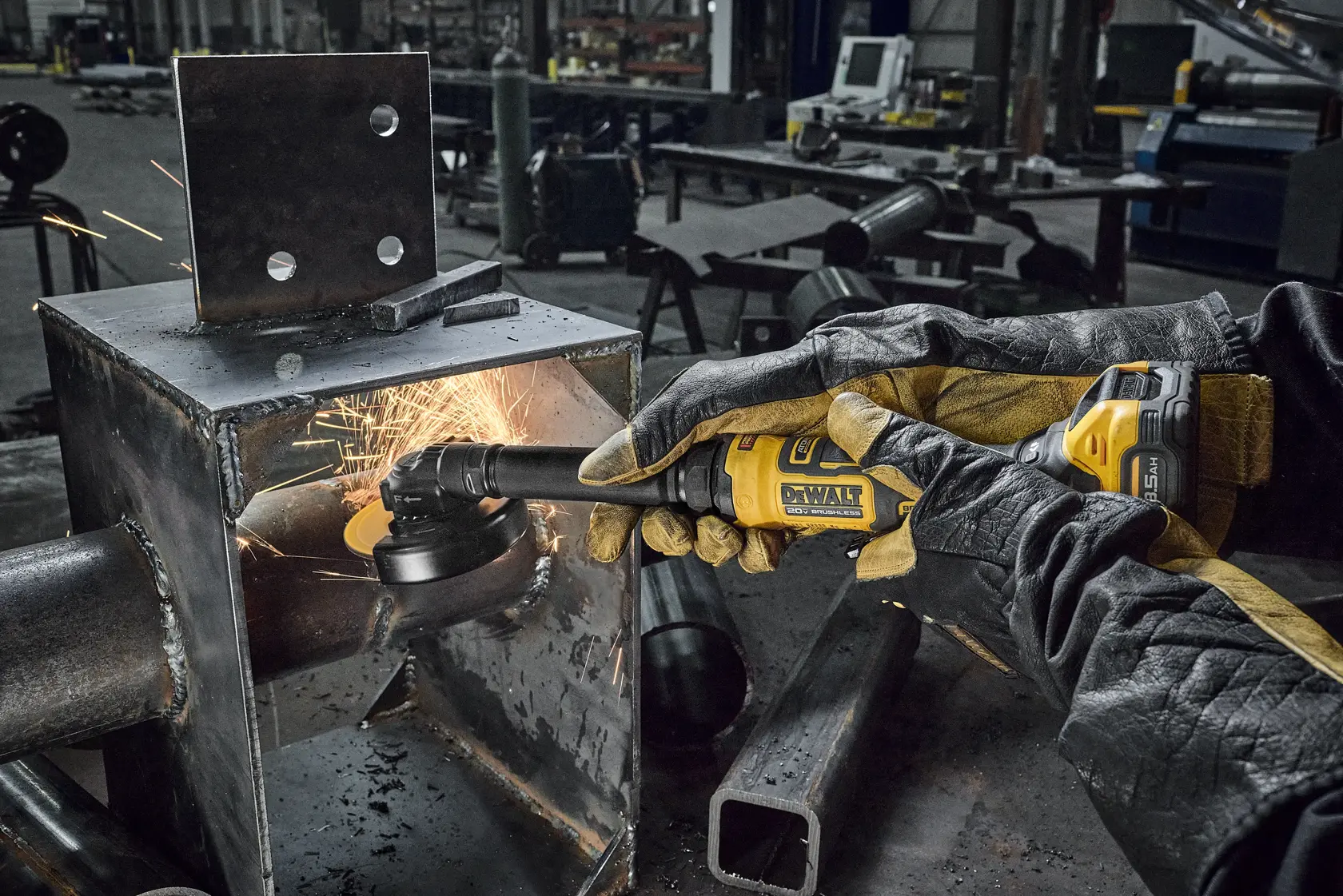 A person wearing protective gloves uses a yellow DEWALT cordless grinder to smooth the inside of a metal structure, producing sparks in an industrial workshop setting.